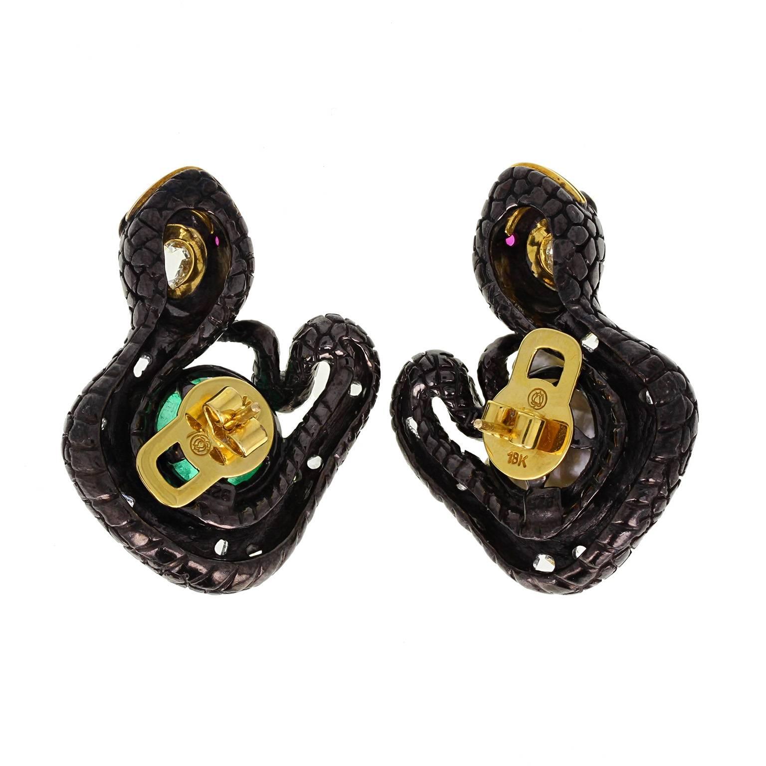 A pair of bold earrings fashioned as a pair of stylised serpents, coiled around a large baroque pearl and a polished, faceted emerald. Crafted from 18 carat gold and silver.
 
Setting
Tests as 18 carat gold and silver
 
Emerald
Weight: 15