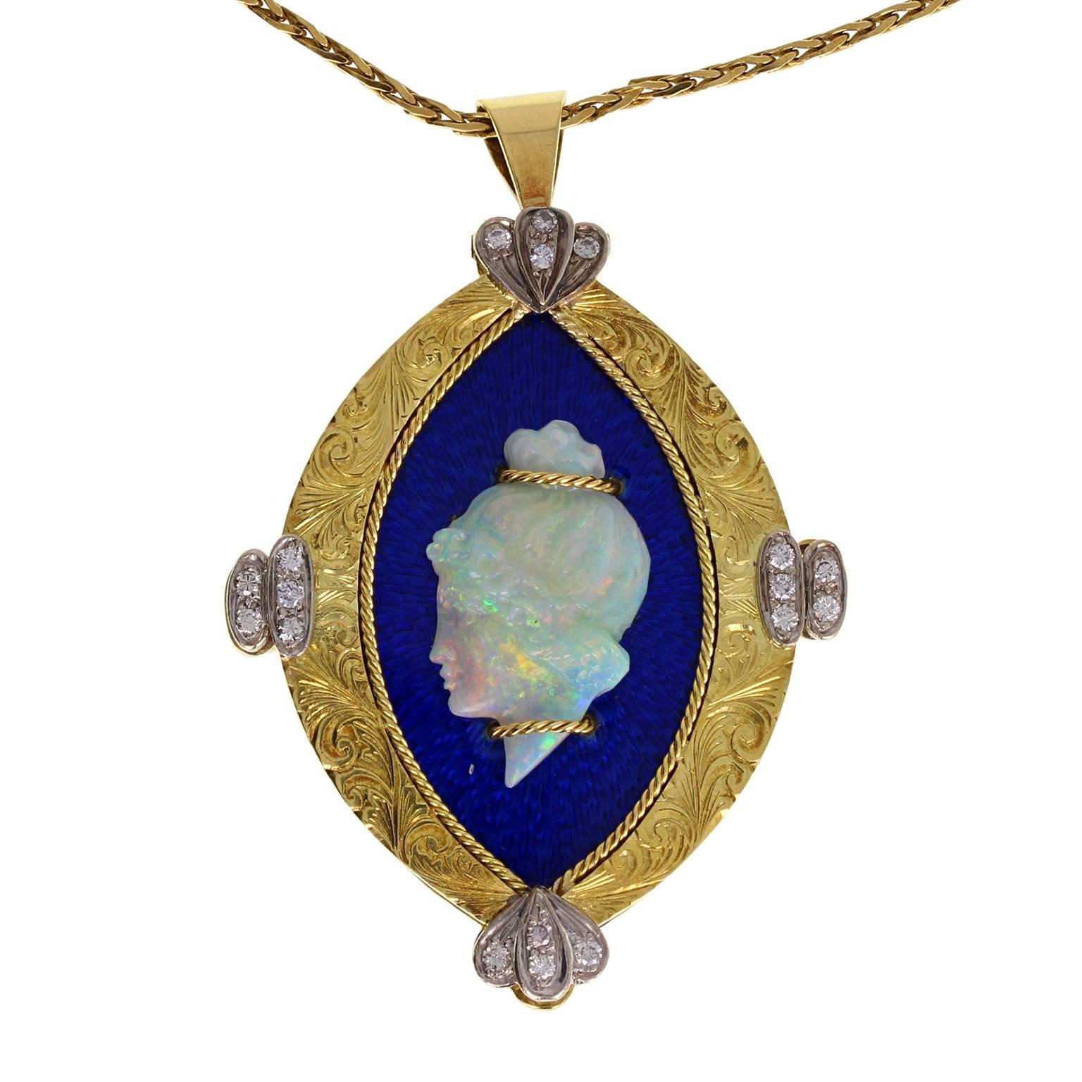 A stylish pendant comprising a carved opal head of a woman, adored with gold, mounted on a blue enamel freize, bordered with an engraved 18 carat gold border, featuring diamond set trefoil detailing. Hallmarked 1974, London. Brooch fitting to rear