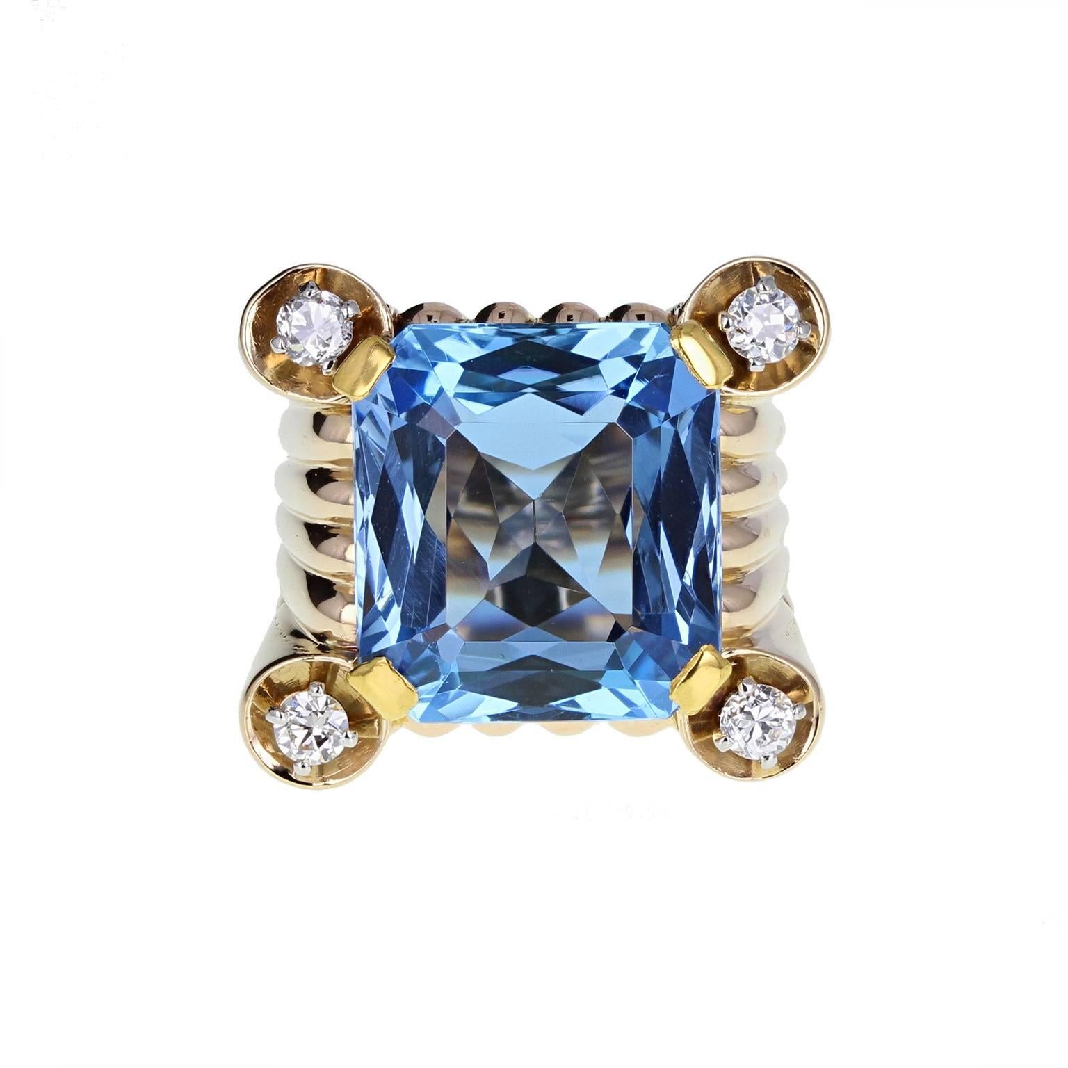 A bold, brave and fine quality cocktail ring from the 1940s. The square, reeded setting mounted with a square radiant-cut aquamarine of astonishing colour. A single brilliant-cut diamond at each corner. The tapering shank is reeded, blending