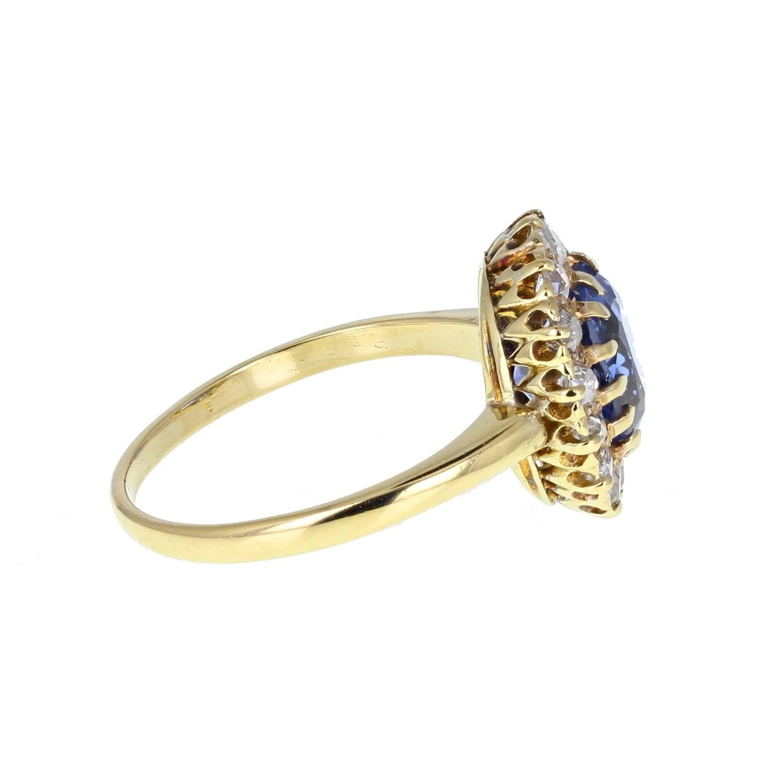 This fabulous, sweet antique ring is set with a cushion-cut blue sapphire of outstanding cornflower blue, with slight nuances of lilac. A beautifully translucent sapphire. Surrounded by a border of old-cut diamonds, all mounted in 18 carat gold