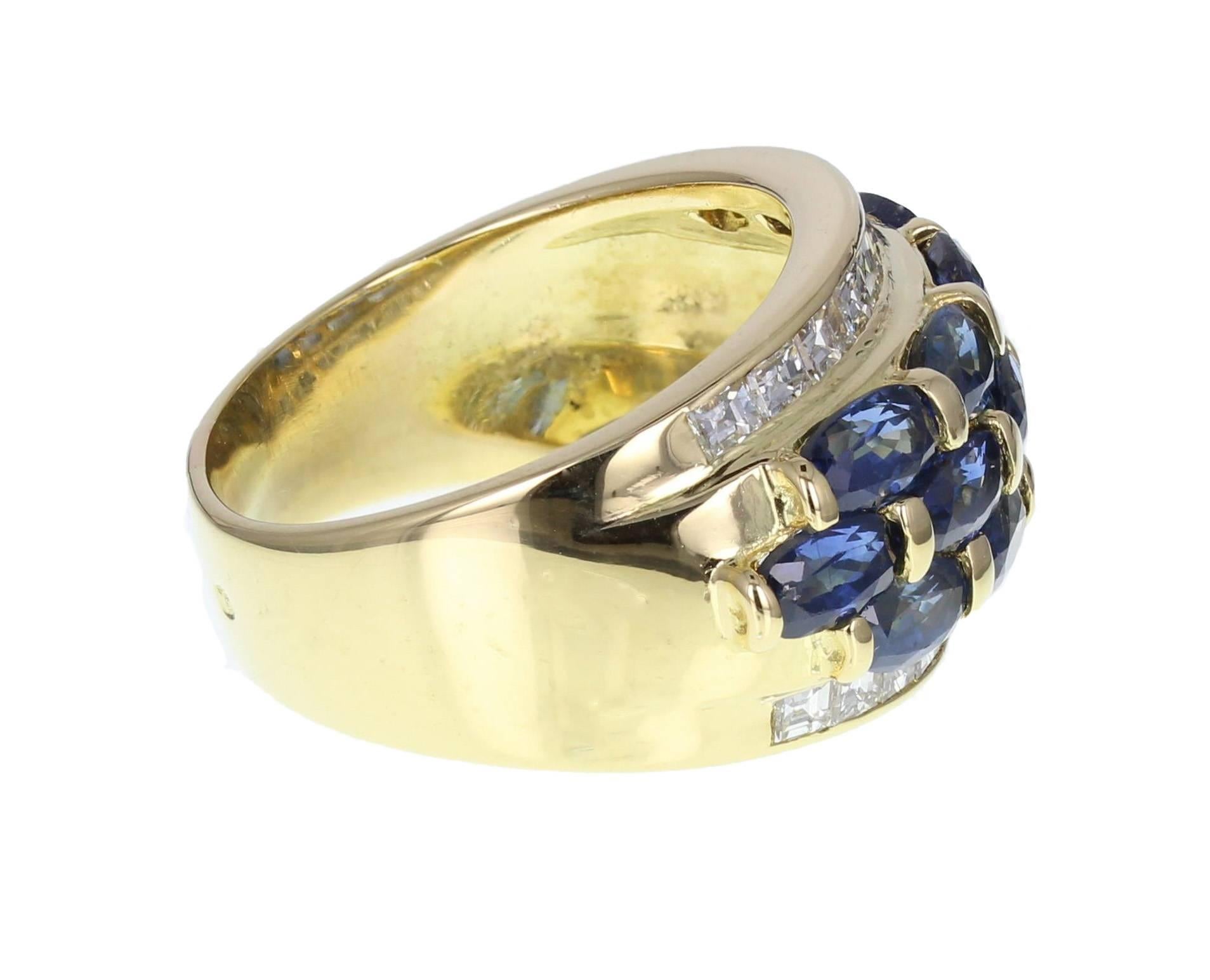 A stunning sapphire and diamond ring comprising a central section of 12 oval cut blue sapphires arranged in a brick style pattern, flanked with a channel set row of step cut diamonds. Sapphires are beautifully matched and of well saturated colour. A