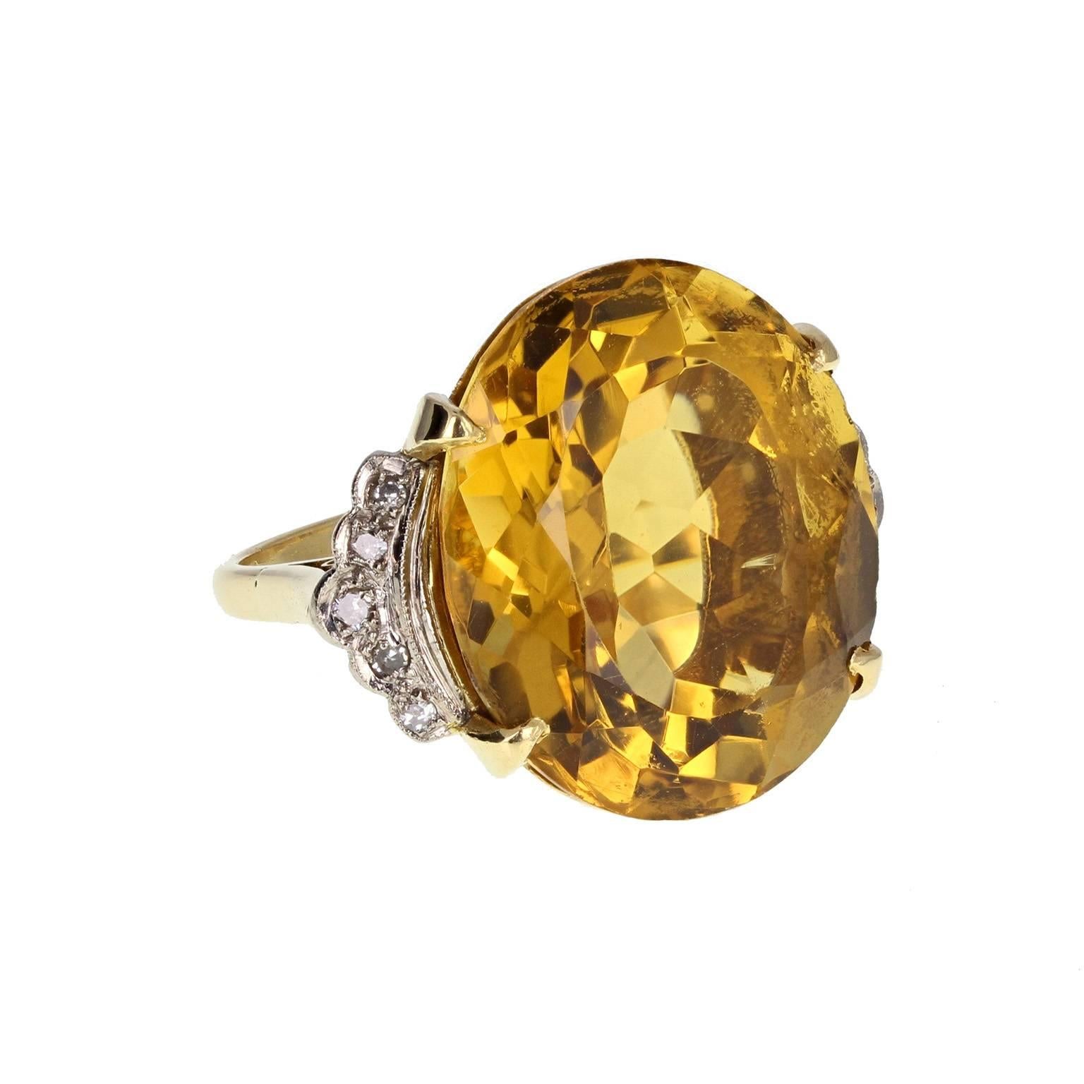 A fine and impressive cocktail ring, circa 1930s. The central oval-cut citrine of deep yellowish-orange mounted in four claws and flanked on each side by five round-cut diamonds in a millgrain detailed accent. A bold and stylish ring. 
Shank and