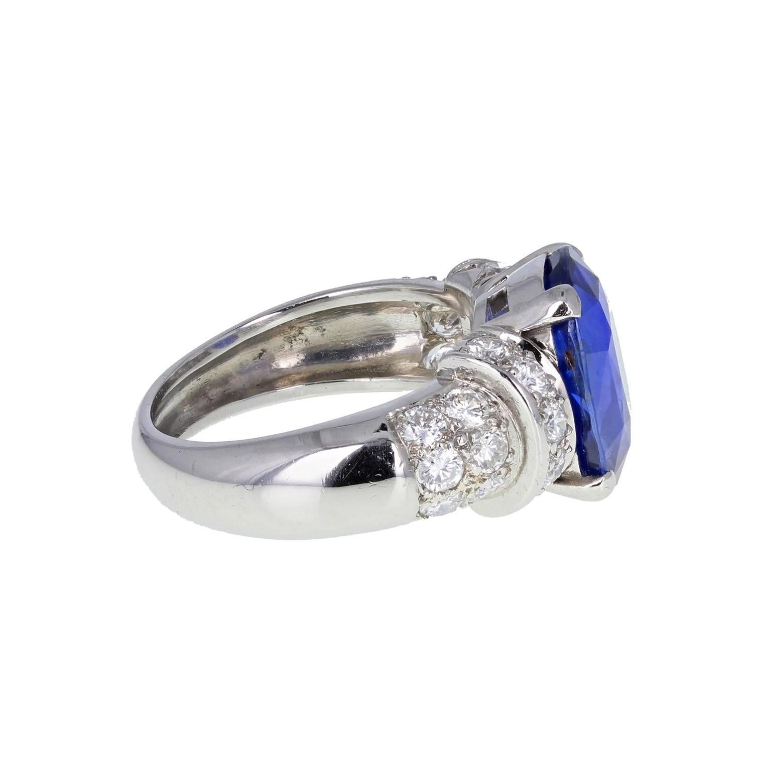 A beautiful ring featuring a central oval-cut blue sapphire, mounted in four claws, flanked on each side by a bar of pavé diamonds, leading to a wide shank, with pavé diamond shoulders. Accompanied by a GCS certificate stating that the sapphire is