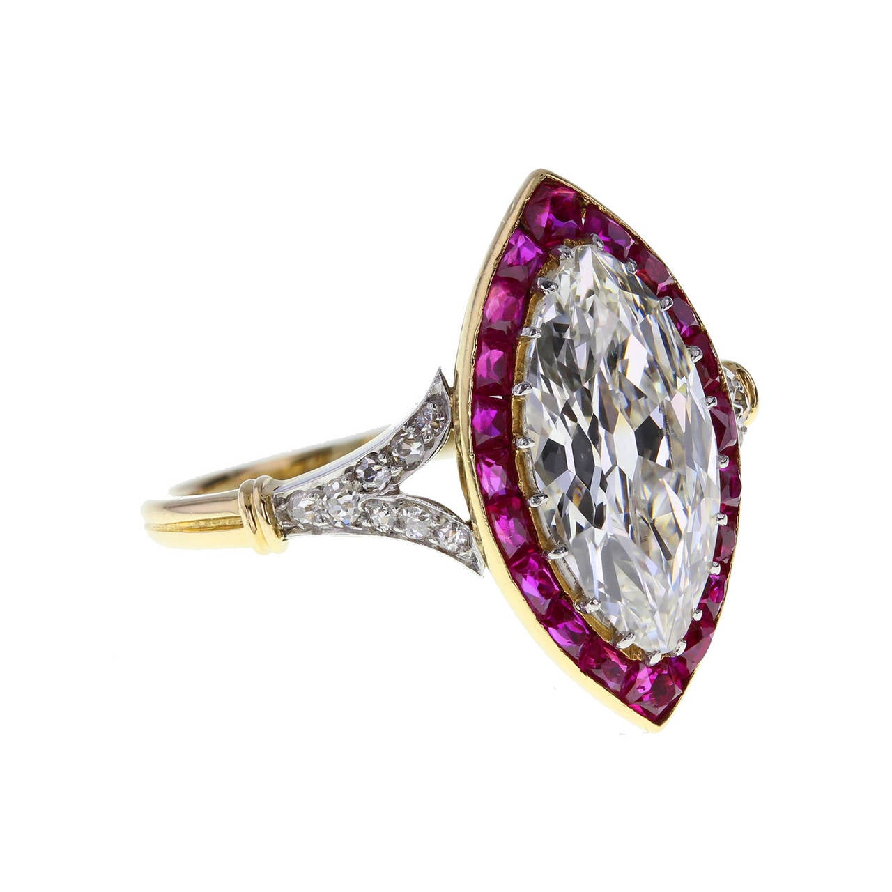 A Belle Epoque platinum and 18ct gold diamond and ruby cluster ring. Circa 1893. The marquise-cut 1.40 carat diamond within a calibre-cut ruby surround, to old-cut diamond bifurcated shoulders and reeded band. Accompanied by a leather folder from
