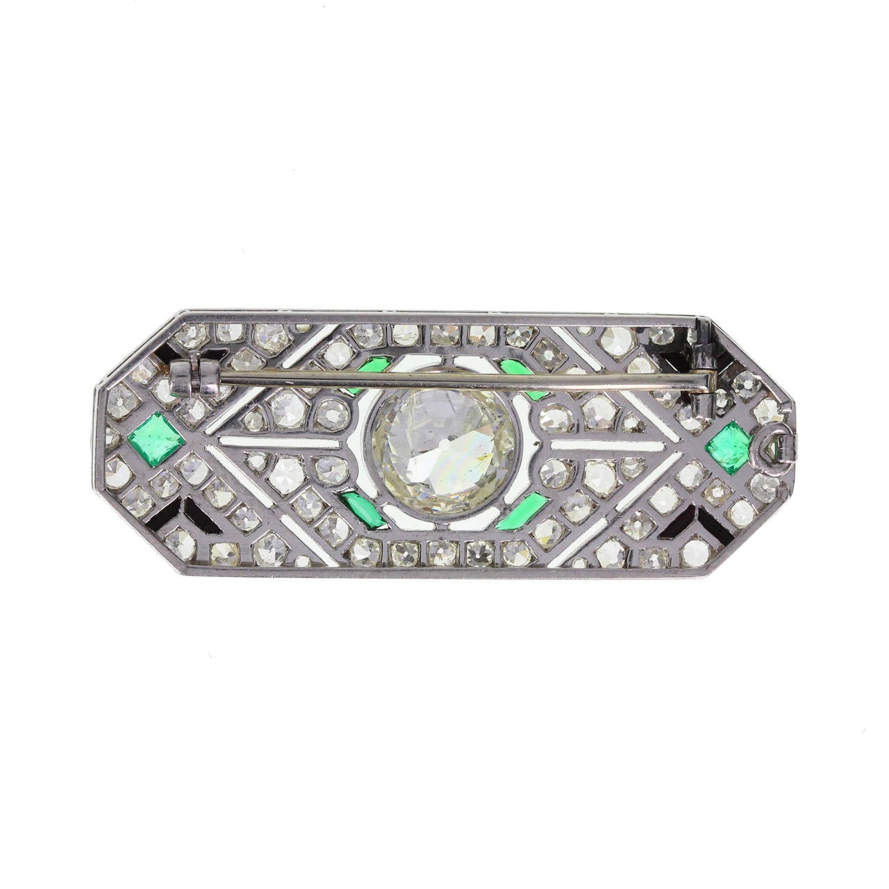 Platinum fashioned in an elongated octagonal shape with pierced detailing. Central 2.75 carat, I colour, P1 clarity diamond in a rub over setting, surrounded by pave set old-cut diamonds in a geometric pattern, accented with square-cut emeralds and