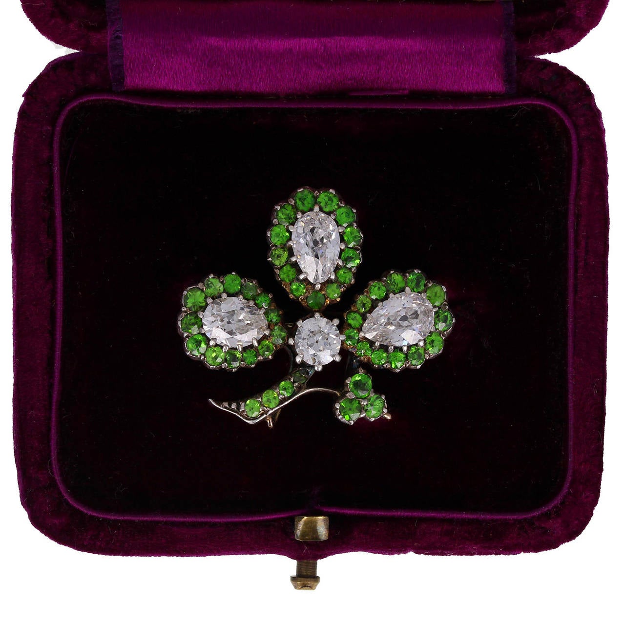 A floral brooch featuring 1.50 carats of very rare round-cut, bright, vivid green garnets bordering three pear-shaped diamonds to form three leaves to a central old-cut diamond extending from a branch. Total diamond weight from four diamonds of 1.80