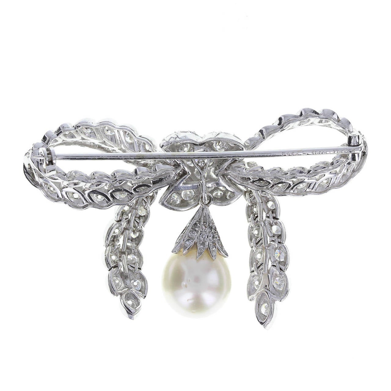 Exquisitely crafted in platinum, each brilliant-cut diamond set it it's own marquise shaped setting. The tails of the bow are articulated and move fluidly when worn. A single cultured pearl hangs from the centre knot of the bow. Total diamond carat