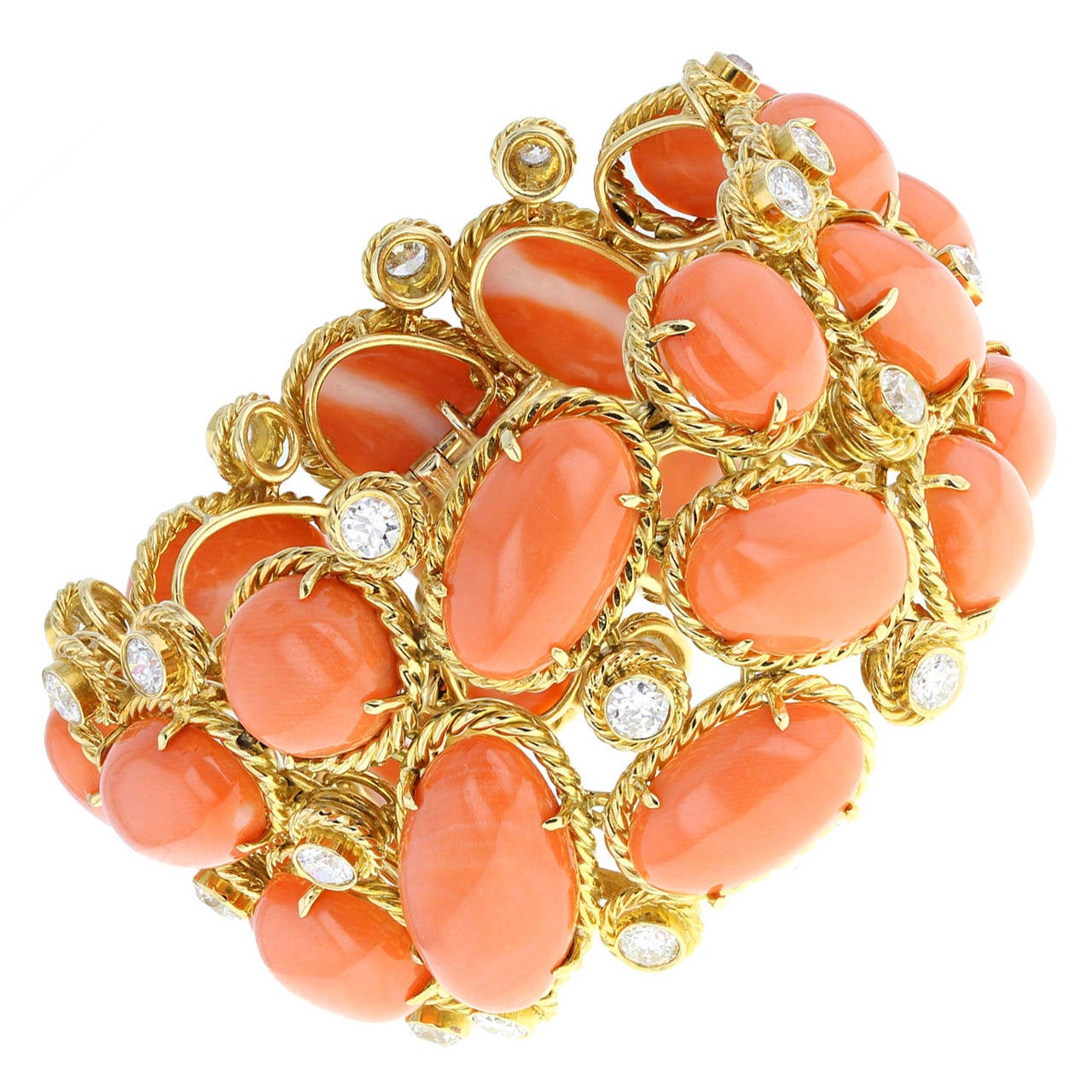 An exquisite wide bracelet formed from oval and round cabochons of salmon pink coral, each claw-set into a rope effect gold border. Mounted randomly together and interspersed with 27 rub-set round brilliant-cut diamonds, also featuring rope effect