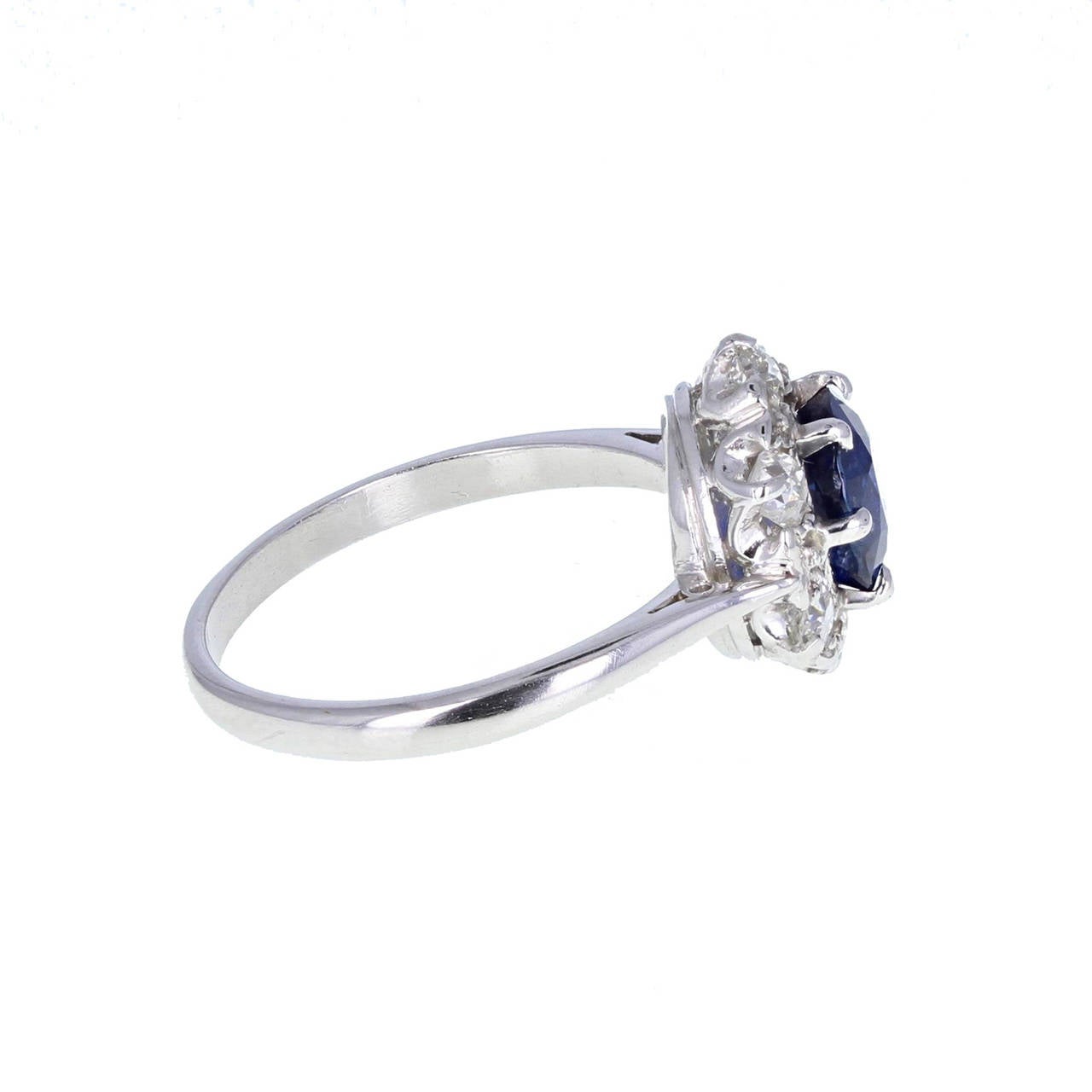 A fantastic quality and exceptional value antique sapphire and diamond cluster ring. Mounted in platinum the central, cushion-cut sapphire exhibits deep, royal blue. Surrounded by old-cut diamonds in a hexagonal shaped setting. Tapering shoulders