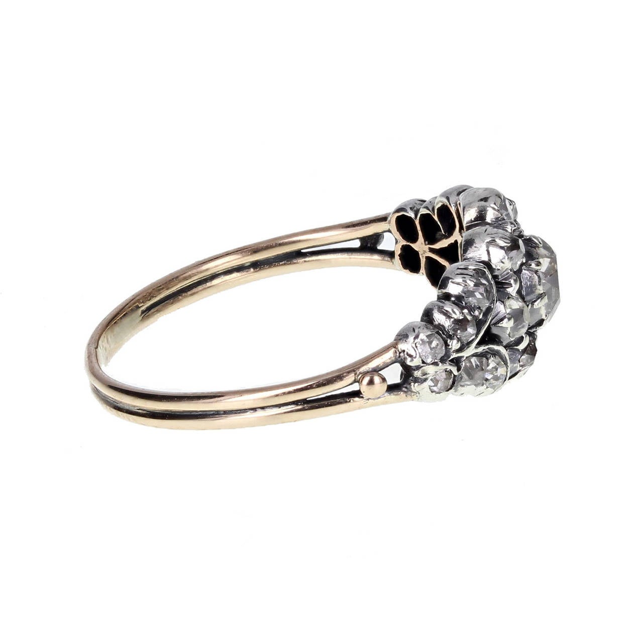This exquisite Georgian ring is typical in period style and of fantastic quality. Old mine-cut diamonds are set in a pierced silver setting, with a larger central diamond, haloed with smaller diamonds and flanked on each side by scroll work. Fine 18