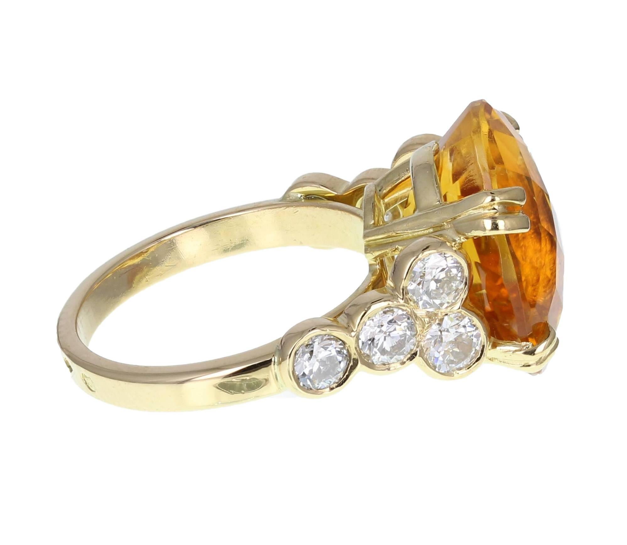 A central faceted oval citrine of stunning vivid orange colour flanked on each side by four round, brilliant-cut diamonds, rubover set on a uniform, squared shank. A fantastically eye-catching ring. 

Shank and Setting
Tests as 18ct gold
