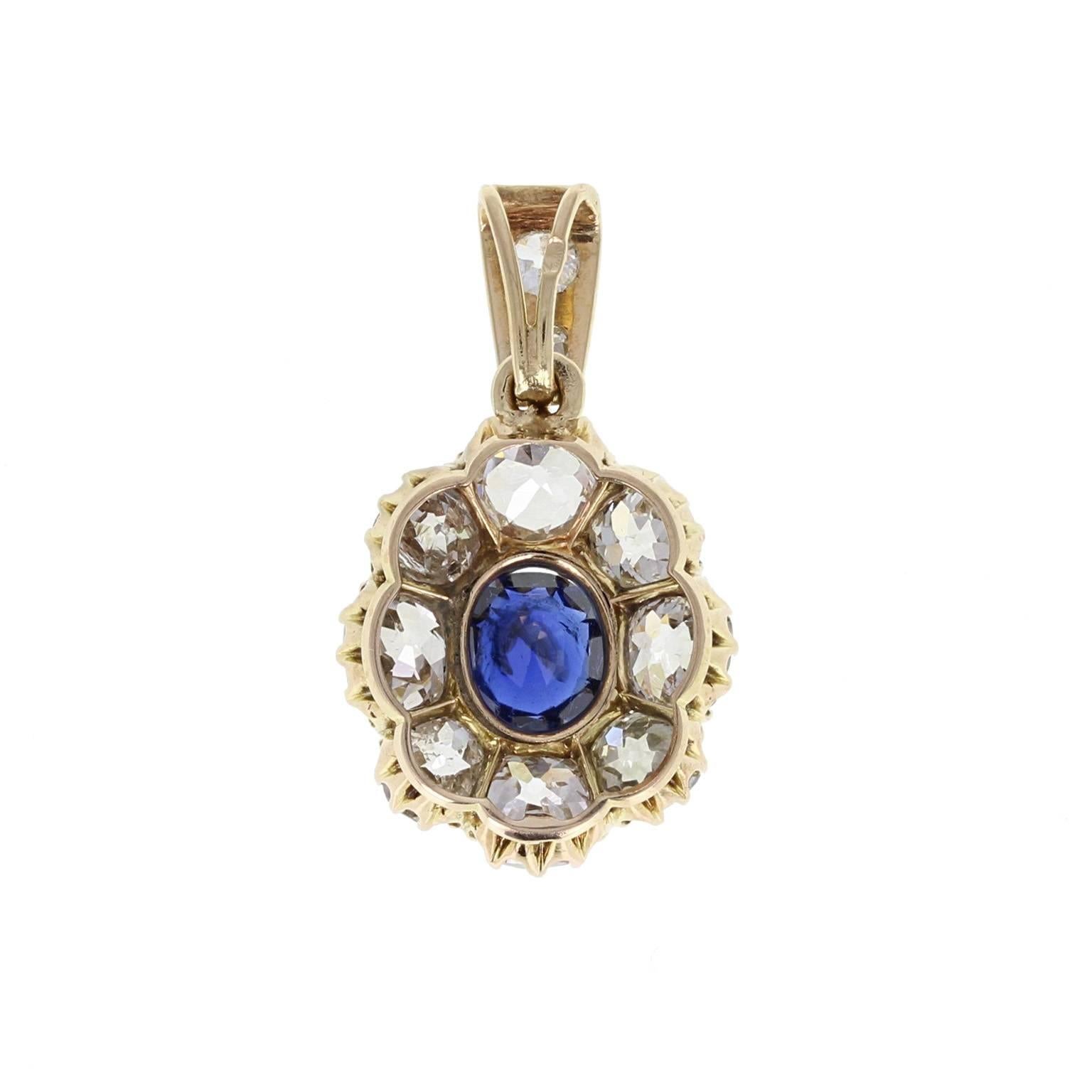 A fine and impressive antique pendant from early 1900s. A central cushion-cut blue sapphire of velvety, deep blue, sits in eight claws, surrounded generously by eight cushion-cut, bright and lively diamonds to form an oval cluster shape. Suspended