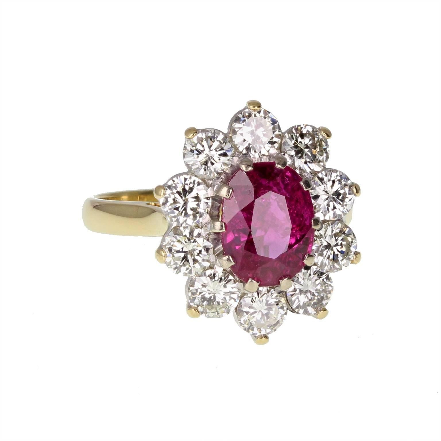 A fine, classic cluster ring featuring a central oval ruby weighing 2.40 carats, surrounded by ten brilliant-cut diamonds to form an oval shaped cluster. Claw set in a traditional basket setting. Simple and elegant, with a fine polished shank.
