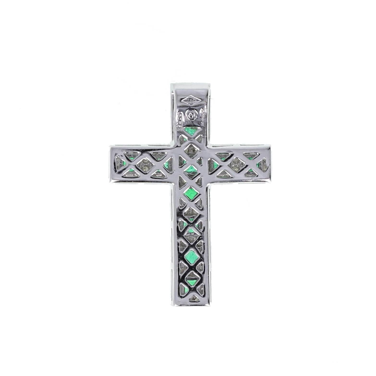 A bright and lively modern cross pendant in 18ct white gold featuring 11 square-cut, well matched emeralds set within a grid border of round-cut diamonds. London hallmark with date letter for 2003. Makers mark 'S & CJ'. 
Setting:
Tests as 18 carat