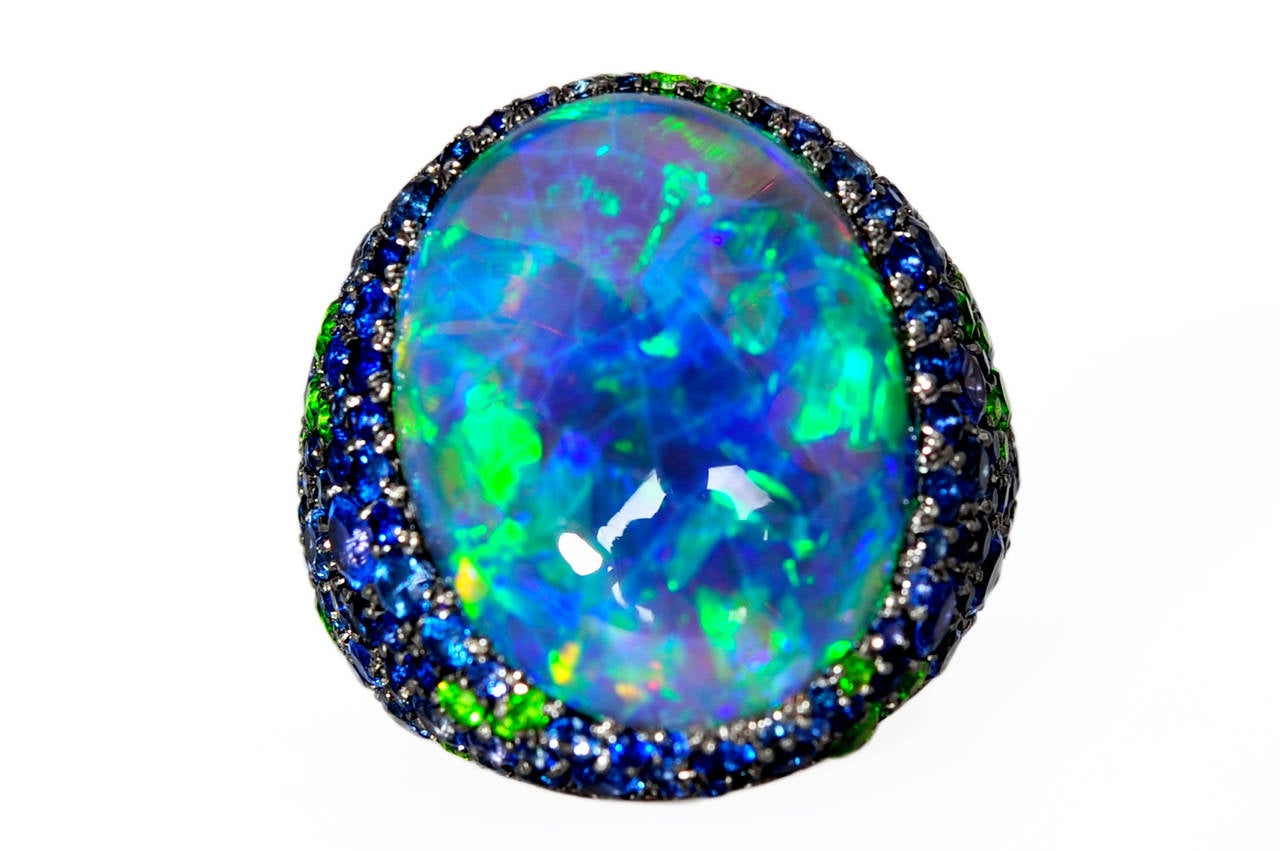 One of a kind lady's cocktail ring showing an Australian solid black opal 14,8ct, beautiful colour play in blue and green, blue sapphire total 5,96ct, vivid green Demantoid garnet total 4,32ct, made of 750WG size 6.5