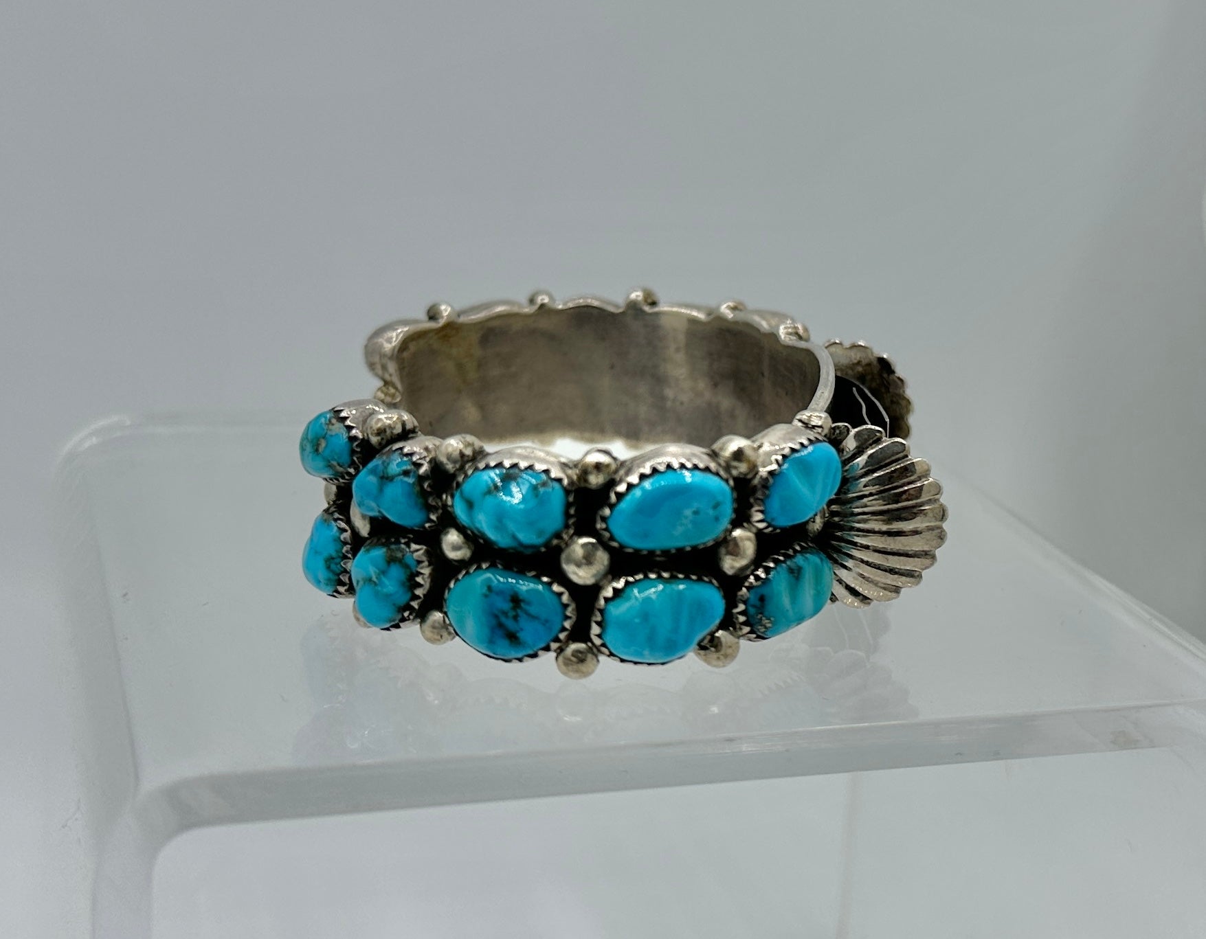 Ésta es una magnífica pulsera de reloj de plata de ley, turquesa y navajo de Orville Tsinnie (1943-2017), con 20 preciosas piedras de turquesa, obra de uno de los galardonados maestros de la joyería navajo.
Nos enorgullece presentar esta