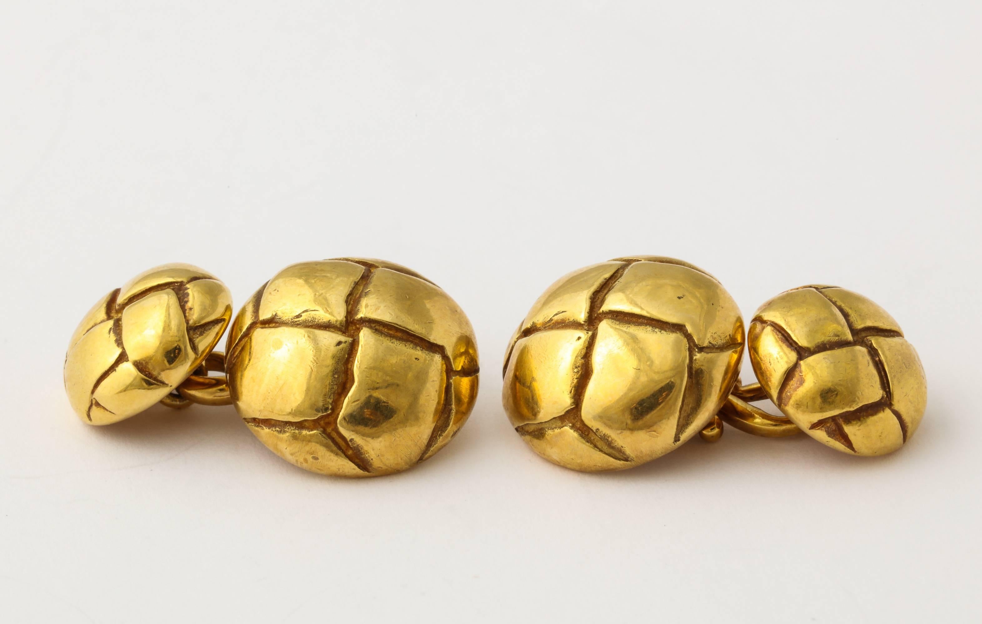 A handsome and sporty pair of Tiffany cuff links of 18K gold, formed as woven  leather covered buttons. .855 grams, 5/8 inch diameter. Marked 1979, with Tiffany and gold marks.