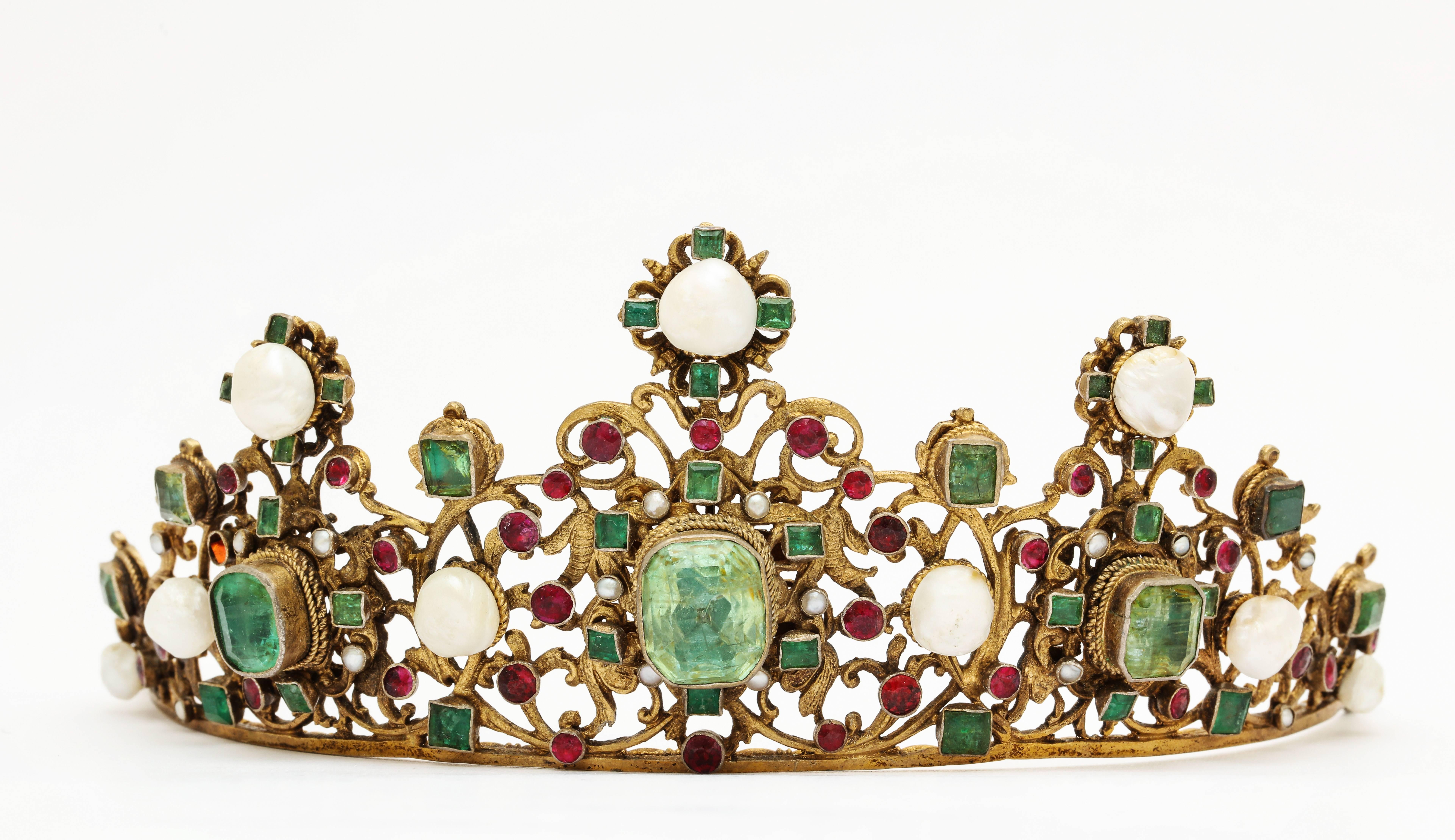Circa 1860 Austro-Hungarian gemstone tiara of gold gilt silver filigree set with emeralds and rubies and highlighted with natural pearls, in original leather travel case. Unidentified marks, 65 grams, 2 1/2 inches x 7 1/2 inches. From a Palm