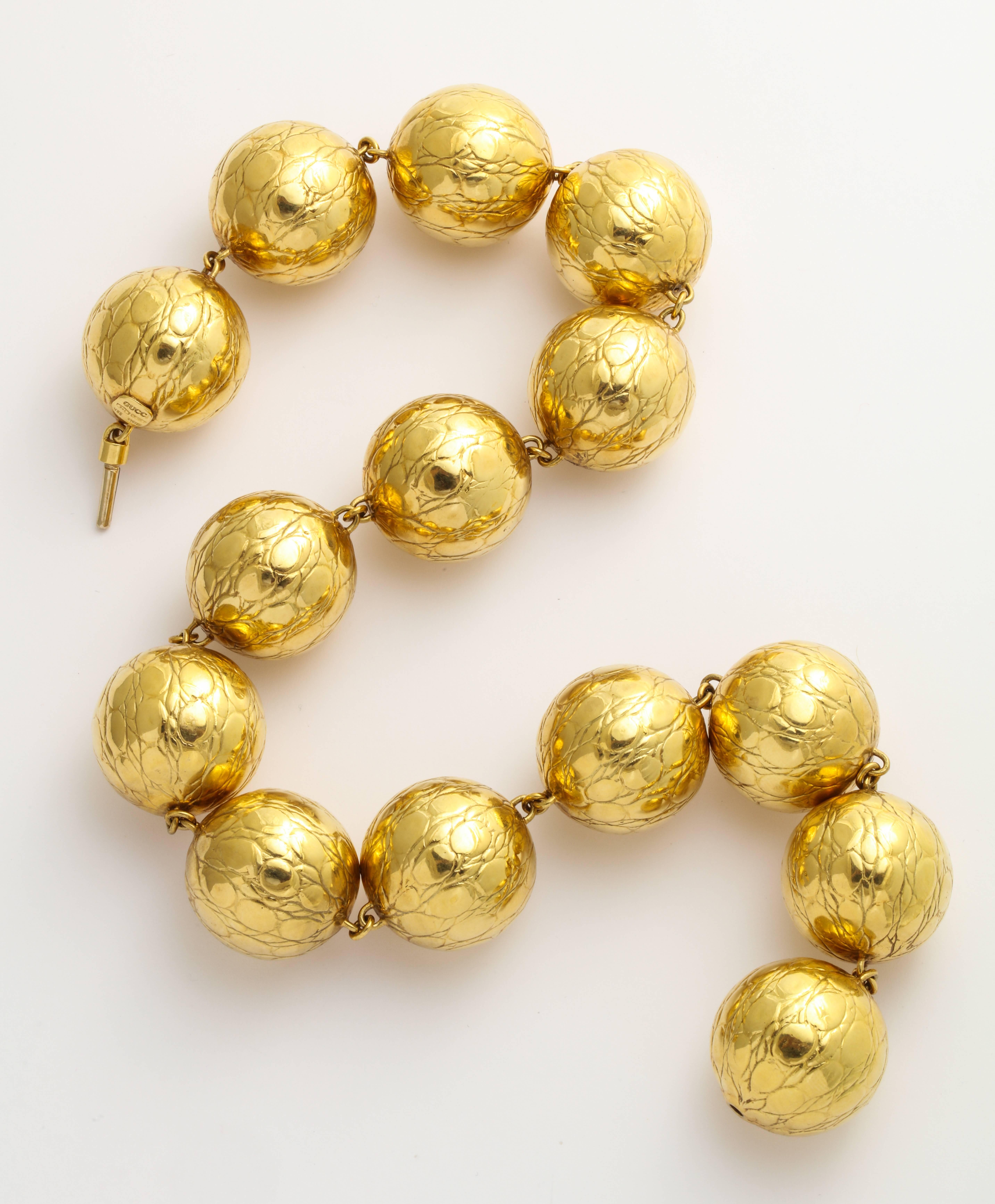 A bold and stunning Gucci necklace of linked 1 inch 18K gold balls with a recessed alligator finish. 18 inches long. Gold mark, Gucci mark, and Italy. 127.7 grams.