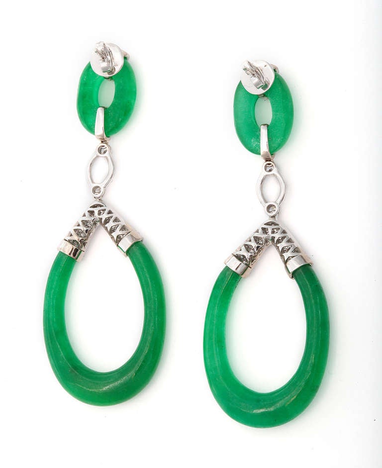 Elegant drop earrings by Sophia D. of 18K white gold set with diamonds, holding carved green jade disks and suspended green jade loops each set with three imbedded diamonds. Marked: Sophia D. and 750.  22.4 grams. 1 inch x 3 inch.