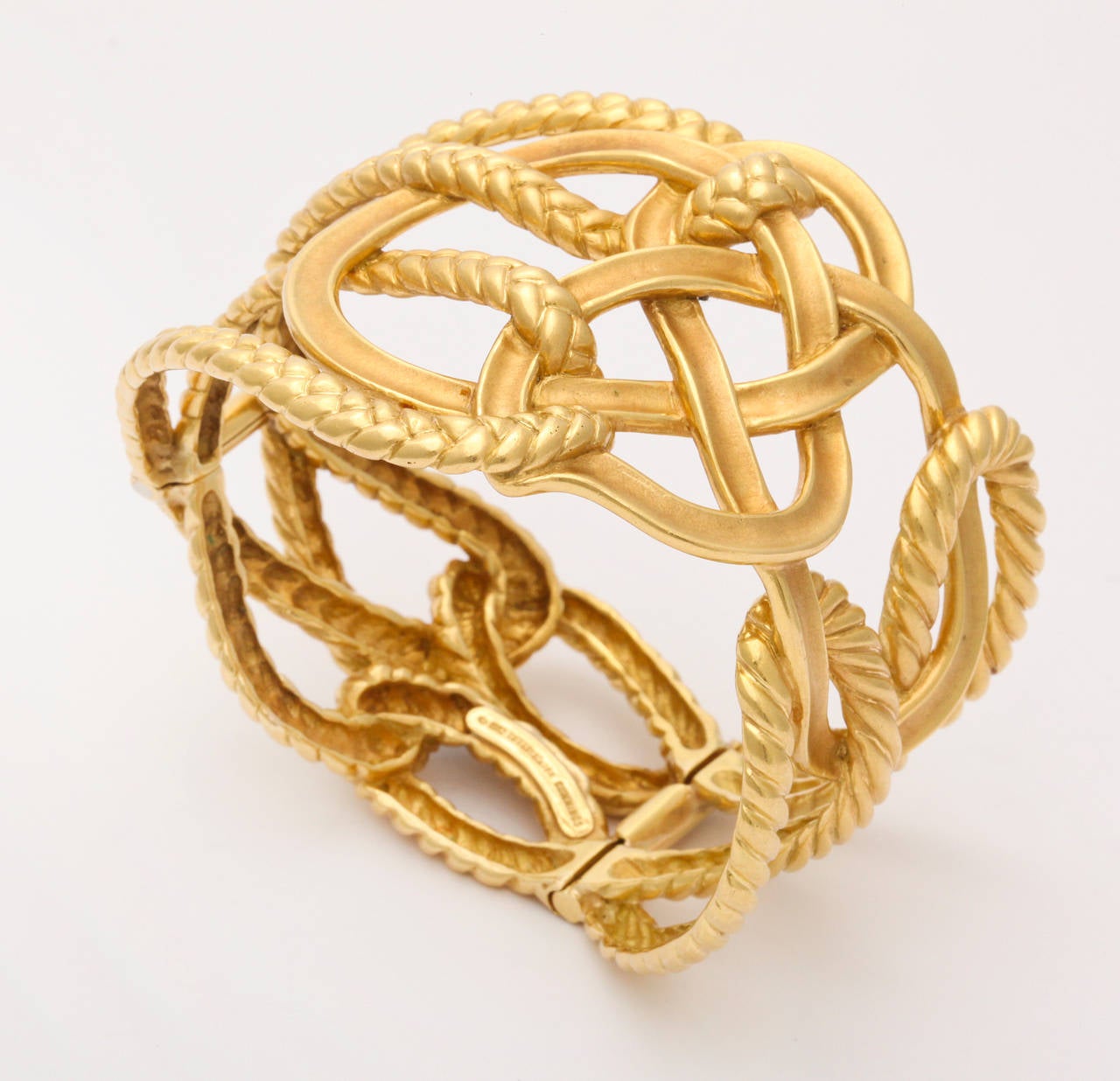 Unusual Angela Cummings bracelet design for Tiffany & Co. in 18K gold, cleverly made in solid form, with the look of loosely woven loops of alternating braided and smooth finished gold. 2 inches at the widest point, and fits a 7 inch wrist. Dated
