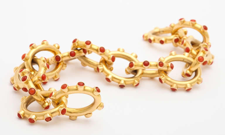 A very chic and contemporary looking 1970s vintage Tiffany & Co. bracelet of 18K gold links set with raised cabachon coral studs, the clasp identified with one cabachon of lapis lazuli. Tiffany, gold, and Italy marks. 8 1/2 inches long, but