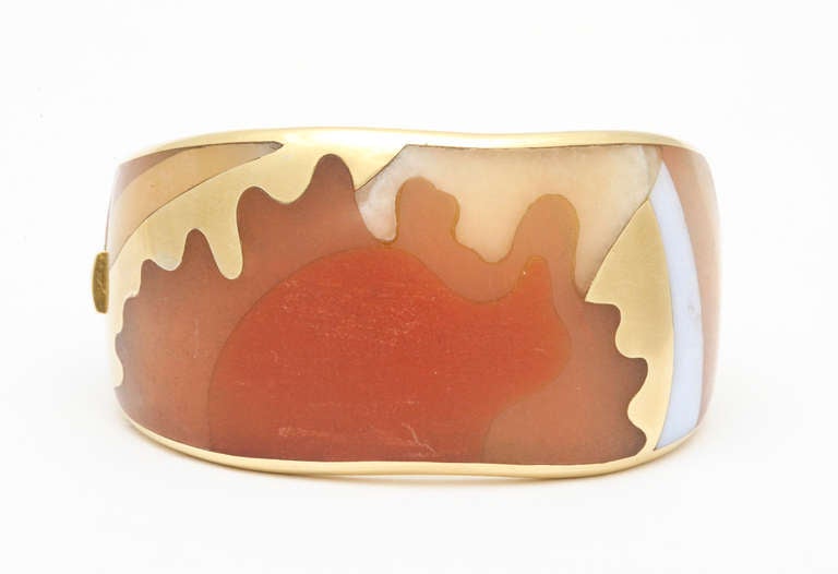 A rare and spectacular 1970s Tiffany bracelet of 18K yellow gold inlaid with various colors of carved agates, fit seamlessly together like puzzle pieces, forming an abstract design of a woman against a sunrise. Marked: T & Co., C, and 18K. 82.7