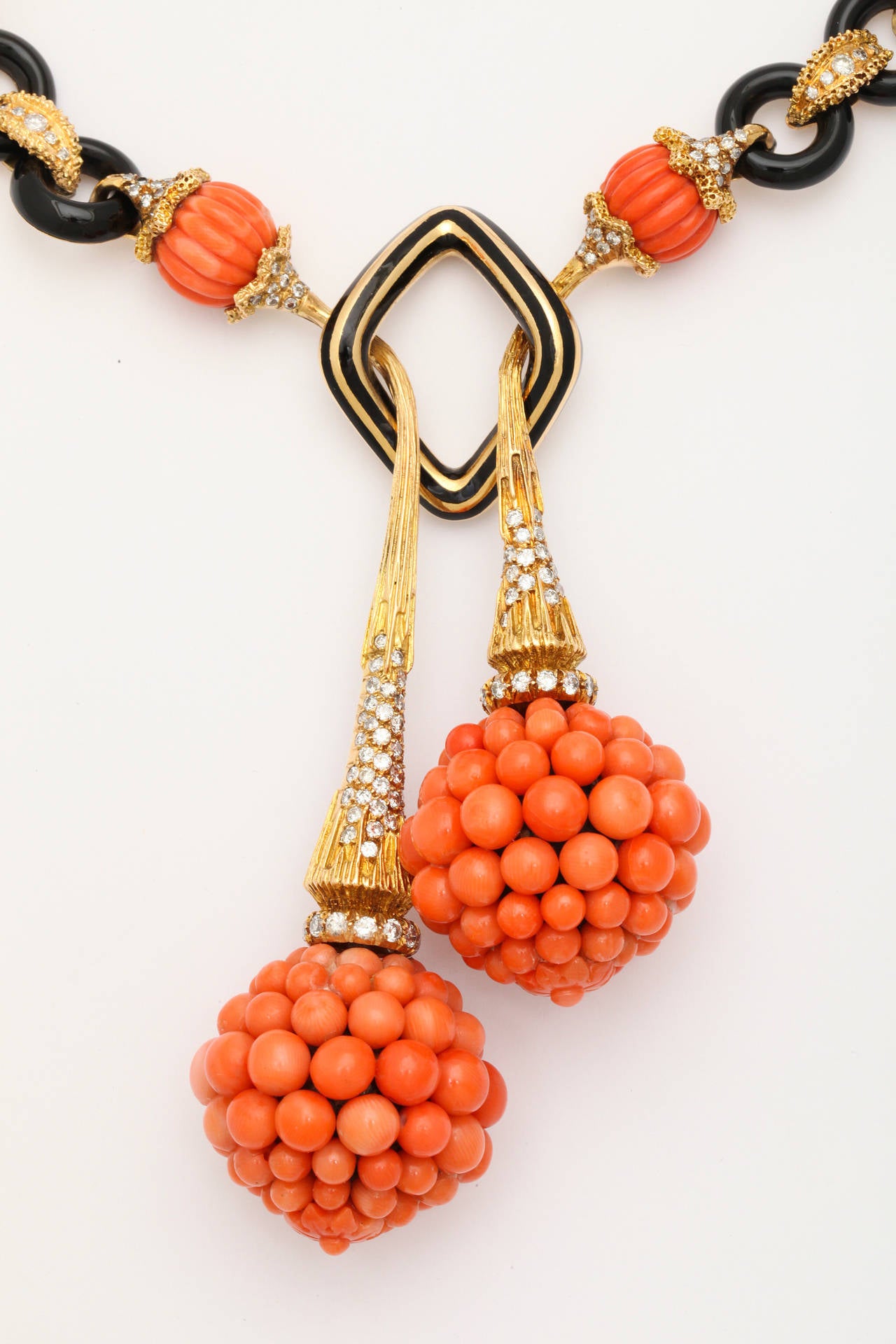 A stunning carved coral and diamond necklace in 18K gold comprised of black coral rings connected by diamond set gold links, and melon carved orange coral beads secured on each side by diamond set caps, two of which appear in the front to pass