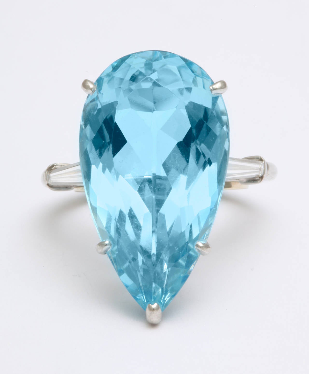 A glamorous 1950s platinum ring by Cartier holding a pear shape 16.88ct natural aquamarine, with long slender tapered baguette diamonds on each side.  Signed Cartier. Aqua measures 1 inch. Currently fits a size 6 finger. With original box, and an