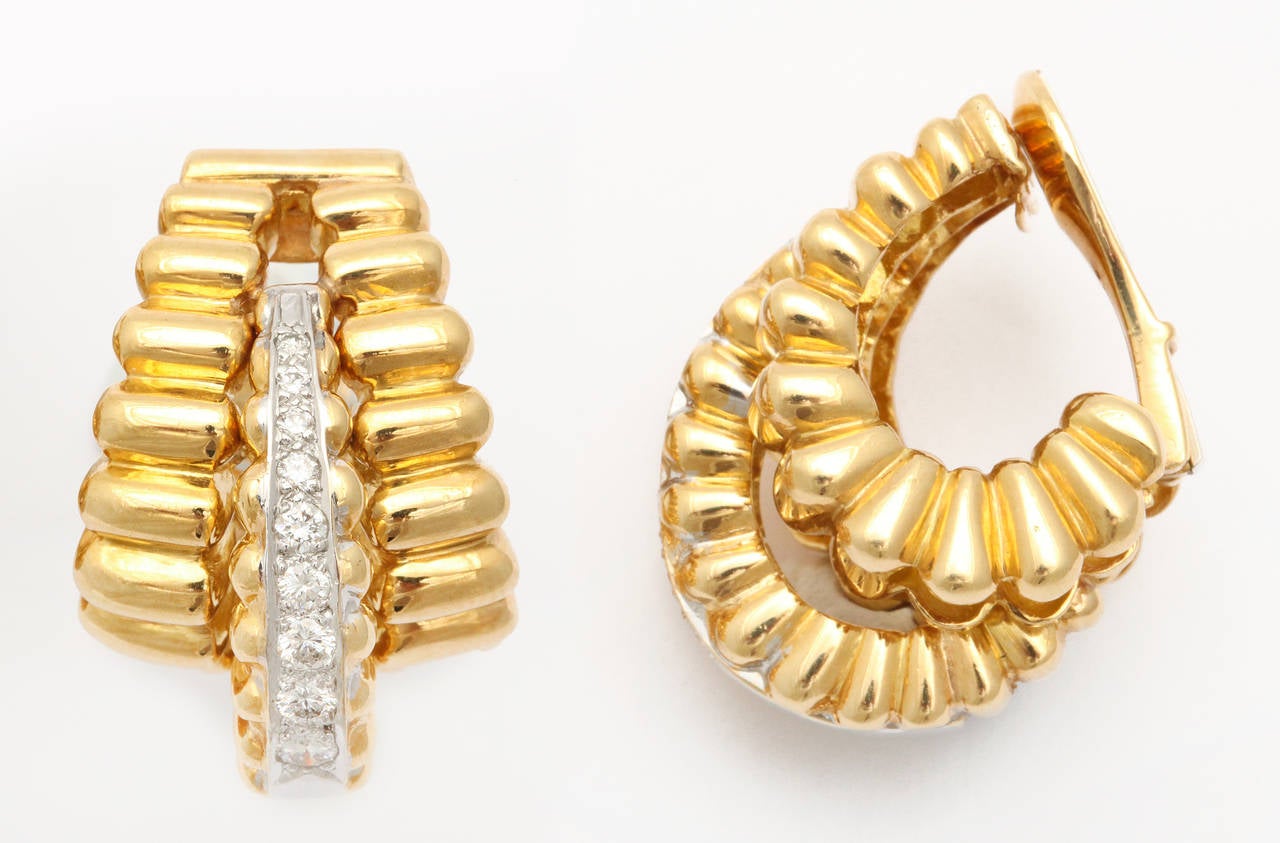 A chic pair of 18K gold ear clips by Robert Wander, formed as three curved and boldly ribbed sections, the protruding centers set with diamonds. The flattering shape wraps under the lobe, and is perfect to wear day or evening. 3/4 inches wide x 1