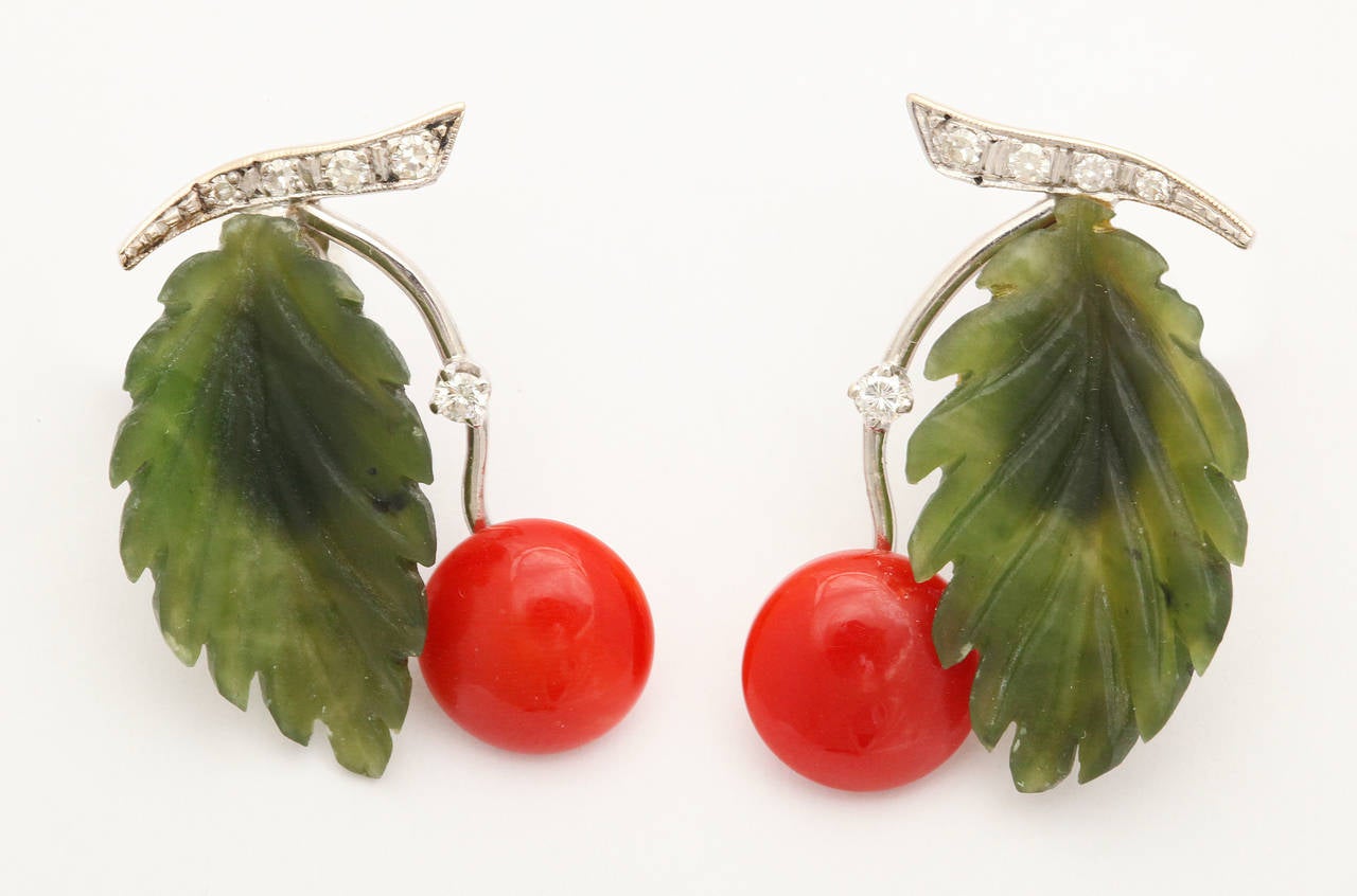 A charming and elegant suite of brooch and matching ear clips by Paltscho of Austria featuring hand carved bright red natural coral cherries on 18K white gold stems, each set with a diamond dew drop and carved green jade leaves. Brooch measures 1