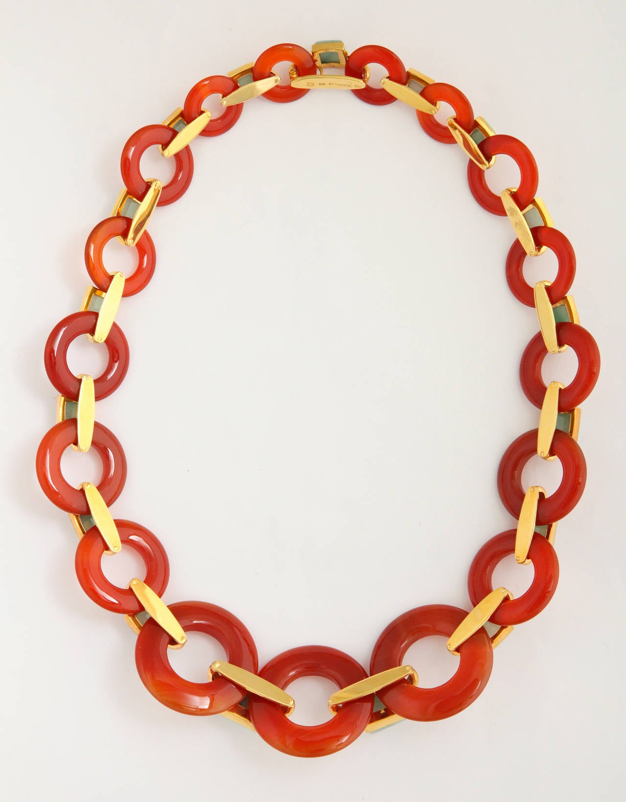 A stylish and fashion-current 1970s necklace by reknown jewelry maker Aldo Cipullo incorporating large graduated "life savers" of hand carved carnelian, connected by 18K gold links set with pyramid cut mottled light green jade elements.