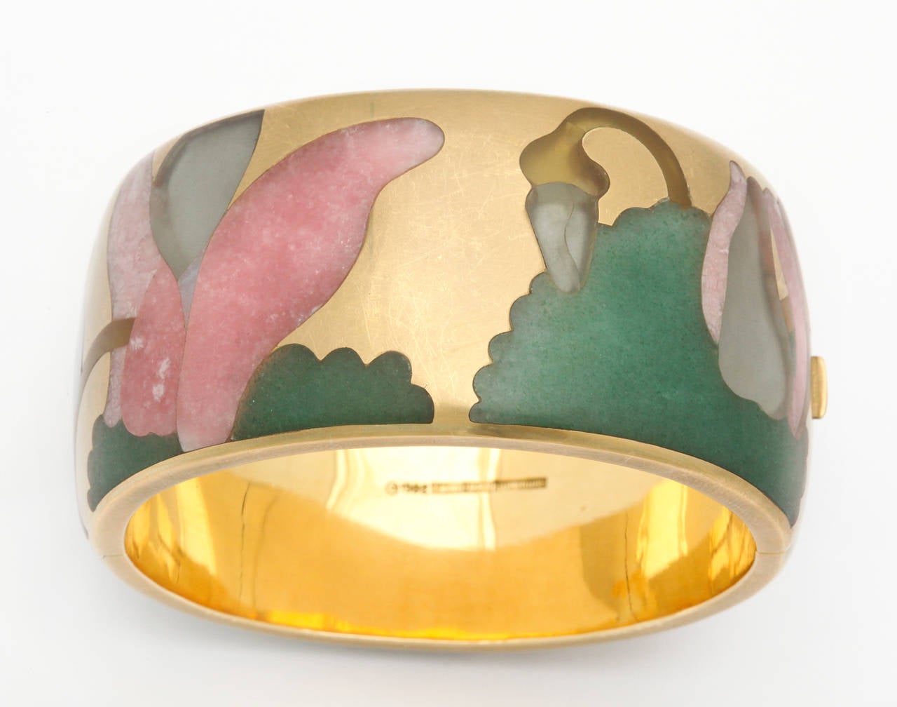 A beautiful 1982 multi stone inlay masterpiece by Tiffany & Co., designed by Angela Cummings. Hand carved multi color hard stones including jade, rose quartz, and rock crystal inlaid like puzzle pieces. The gold surface of the bracelet has a very