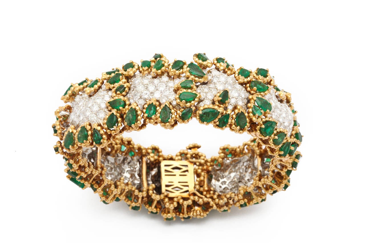 A spectacular 1960s bracelet by Wander - Paris as abstract flowers comprised of 102 pear shape dark green emerald petals (82.02 carats) and 229 round brilliant and single cut diamonds (5.72 carats GH/VS) set as undulating flower centers. Measuring 1