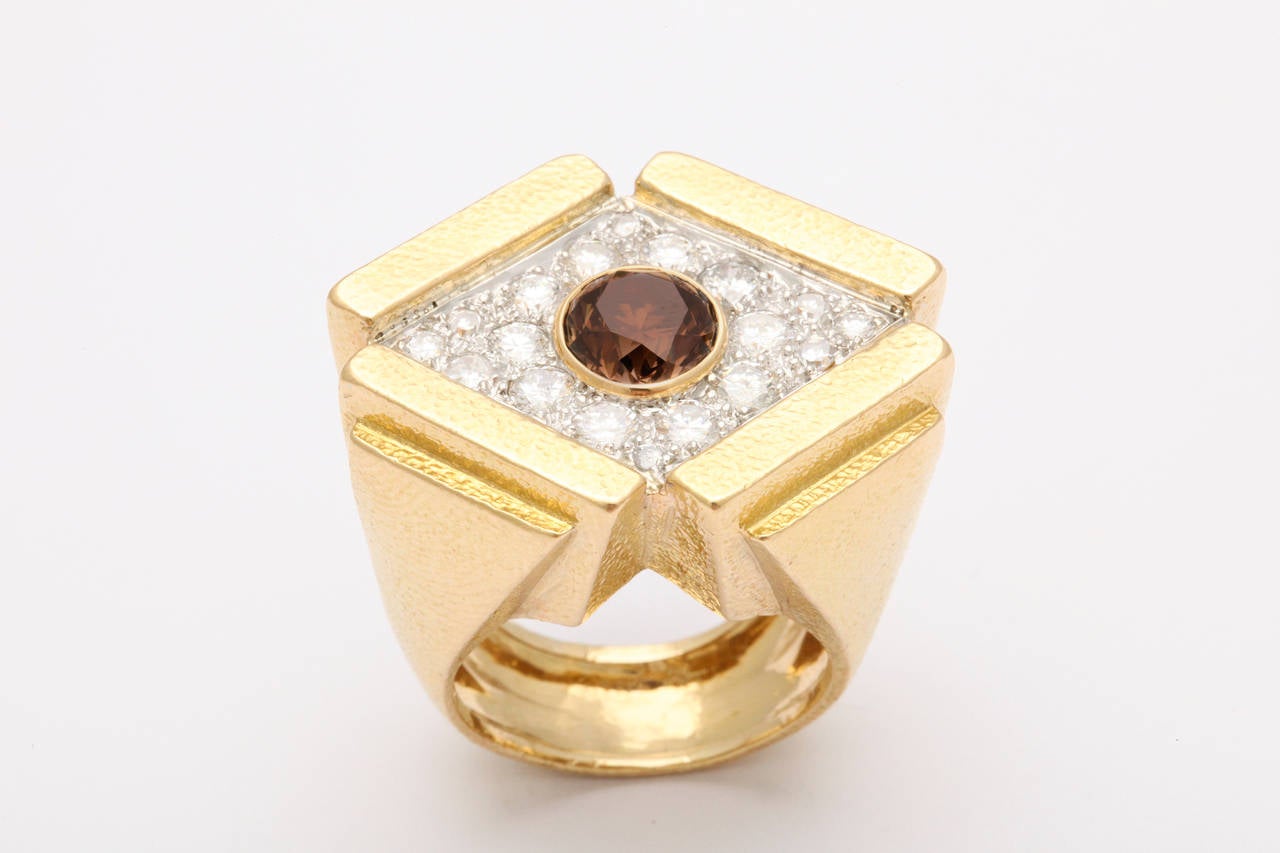 A stunning 1980s geometric ring design by David Webb of textured 18K gold, set with a lively natural brown diamond of approximately 1.5 carats, nested in a bed of bright white diamonds. The architectural effect would seem inspired by Webb's New York