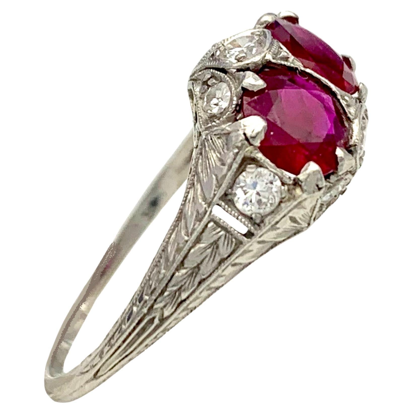 This elegant ruby and diamond ring is mounted in a beautifully chiselled and engraved setting typical for the period between 1910 and 1920. The platinum ring is decorated with foliage on the ring shank. The ring head is set with two natural rubies