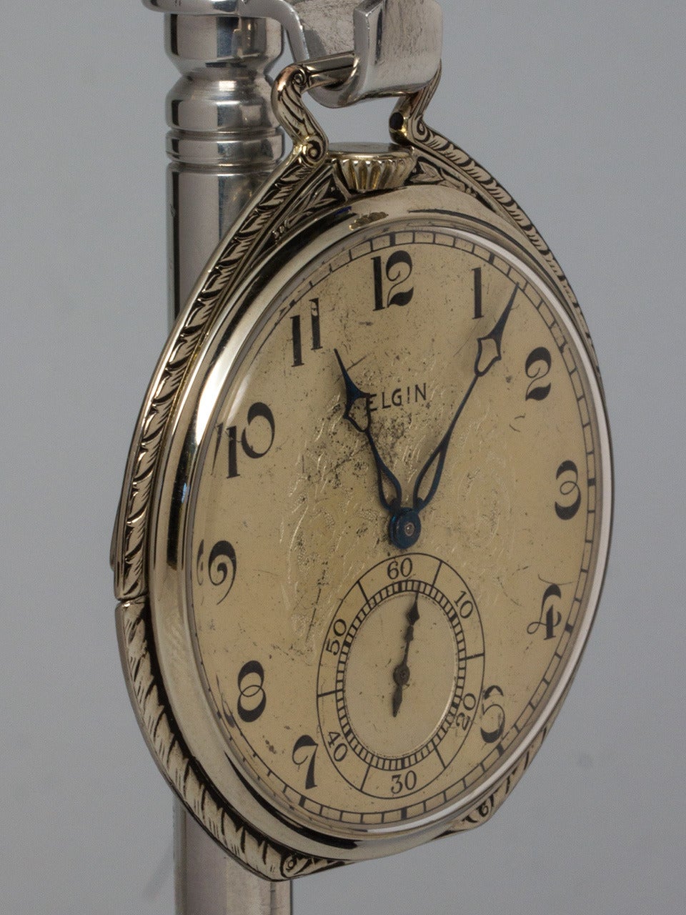 Elgin White Gold-Filled 12-size open face pocket watch, circa 1930s. Case has fold down outer ring to the back for use as nightstand watch. Very pretty engraved outer bezel. Original lightly patinaed dial with highly stylized Arabic figures, blued