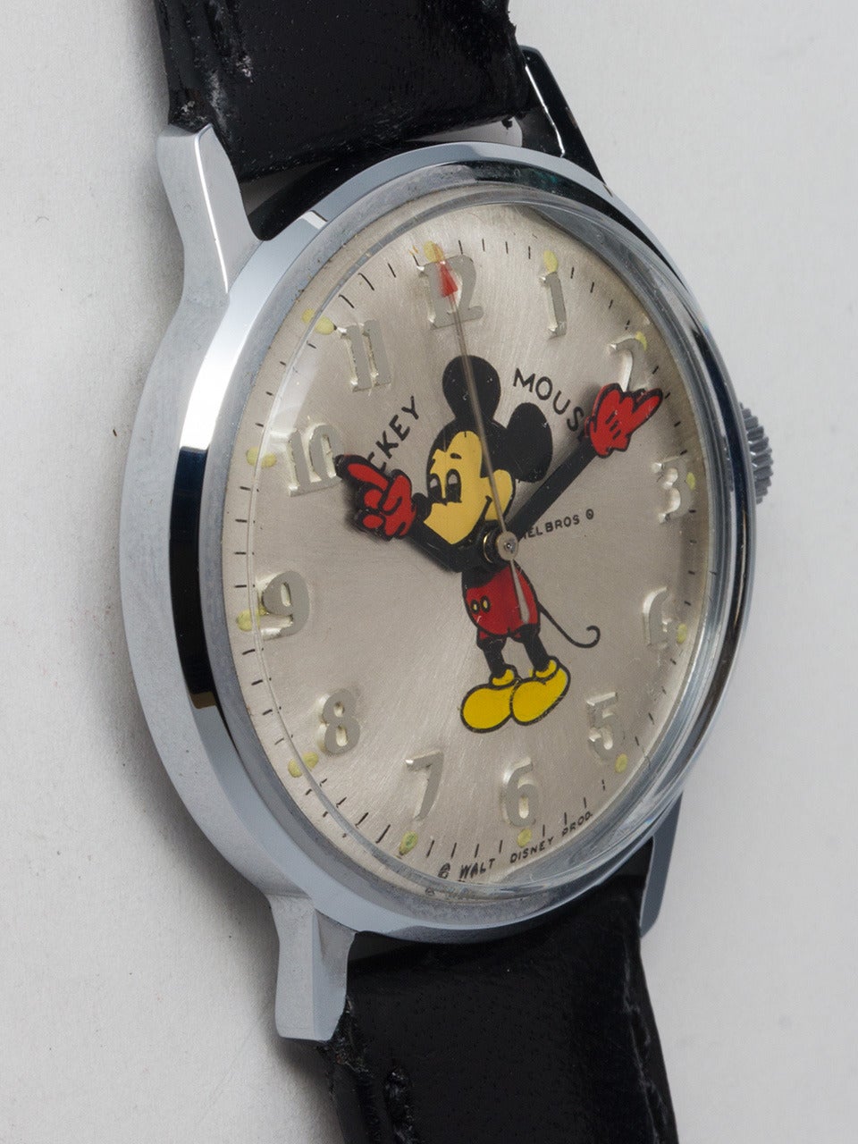 Adult-sized Helbros stainless steel and base metal Mickey Mouse wristwatch, circa 1970s. 34 x 39mm case with acrylic crystal. Lovely silvered satin dial with raised Arabic numbers, colorful image of Mickey with animated red gloved hands. Powered by