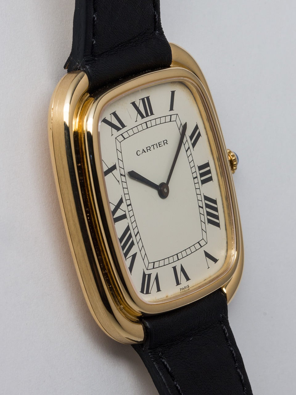 Cartier 18K Yellow Gold Cushion Form Wristwatch, introduced in 1973. Oversized 35 x 40mm case with rounded, stepped bezel design. Very striking and pleasing design with classic white Roman dial, blued steel hands, and cabochon sapphire crown.