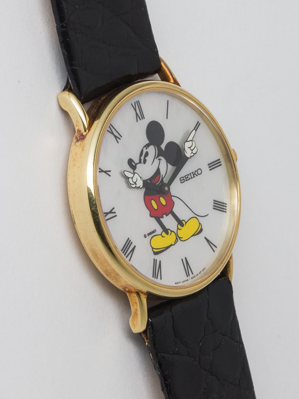 Seiko 14K Yellow Gold Mickey Mouse Limited Edition Wristwatch circa 1980's. Striking mother of pearl dial with polychrome image of Mickey and animated gloved hands. Battery powered quartz movement. Case measuring 35mm diameter. With original black