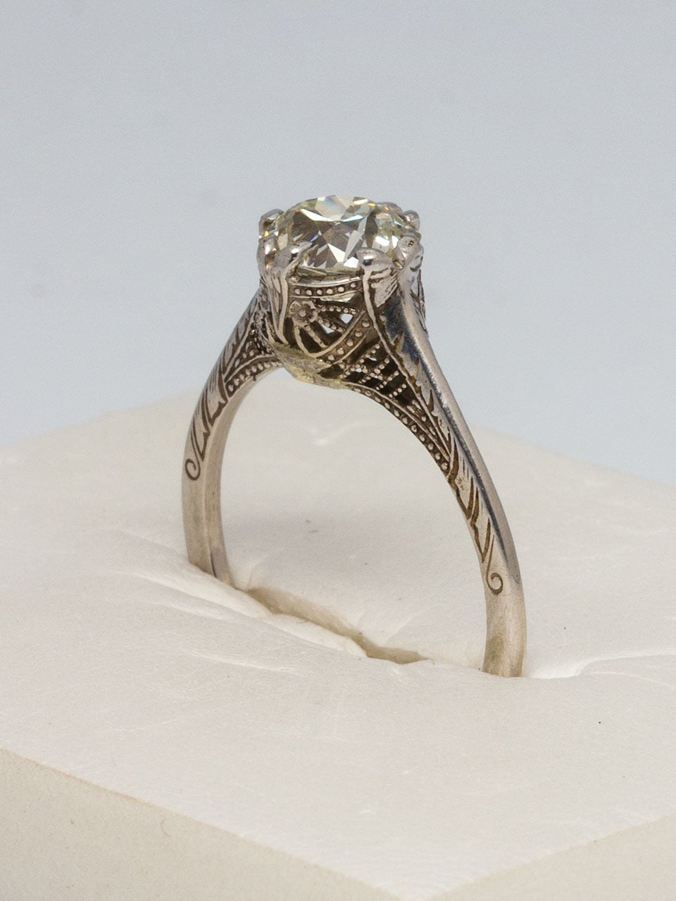 This stunning antique 14k white gold solitaire engagement ring features an absolutely stunning 1.12ct Old European Cut diamond center stone, K-VS2. The elevated setting is beautifully embellished with intricate and expertly executed filigree detail