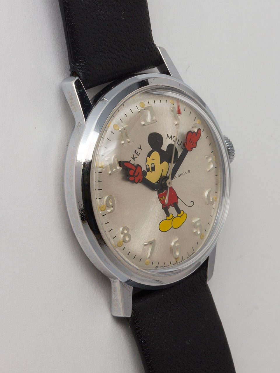 Adult-sized Helbros stainless steel and base metal Mickey Mouse wristwatch, circa 1970s. 34 x 40mm screw back case with acrylic crystal. Lovely silvered satin dial with raised Arabic numbers, colorful image of Mickey with animated red gloved hands.