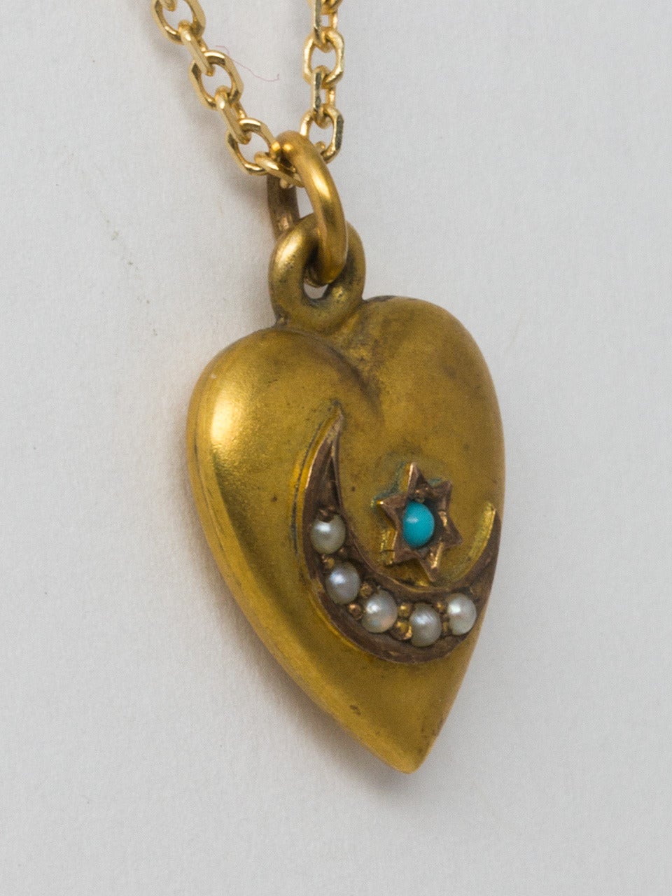 Victorian 14K yellow gold  puffed heart pendant with sweet crescent moon and star design on front. The crescent moon is adorned with small pearls while the six pointed has a turquoise. Hand engraved 