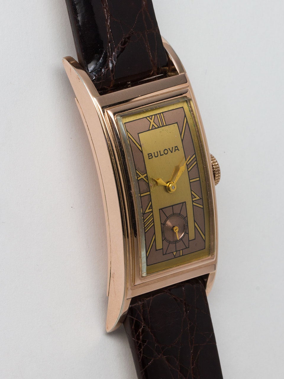 Bulova Rose Gold Filled Elongated Curvex Style Wristwatch circa 1940s. 20 X 46mm case with stepped sides. Very pleasing original 2 tone salmon and gold mirror Arabic numeral dial. Powered by 17 jewel manual wind movement with subsidiary seconds.