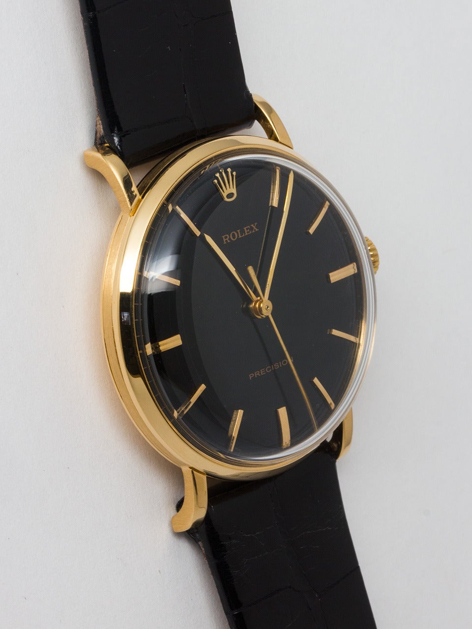 Rolex 18K Yellow Gold Dress Wristwatch circa 1960. 35mm diameter case with acrylic crystal and beautifully restored glossy black dial with applied gold indexes and gilt baton hands. Powered by Rolex caliber 1210 17 jewel manual wind movement with