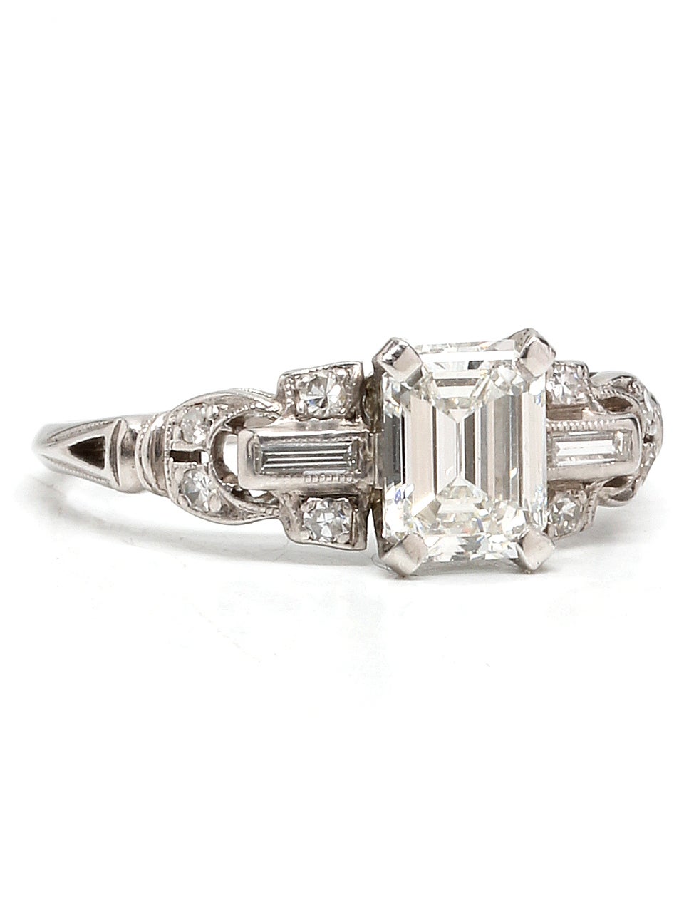 Striking platinum engagement ring. Featuring a 0.94 carat Emerald Cut diamond center stone, H color VS2 clarity. Each side is flanked with 4 round and 1 straight baguette accent diamonds adding approximately 0.17 carat. 
Size 6 Circa 1930's
EGL US