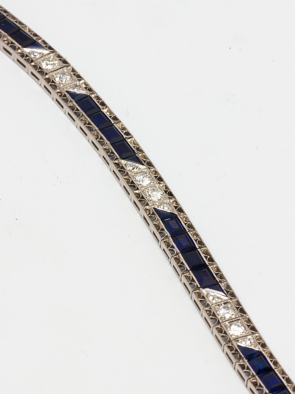 Lady's platinum Art Deco line bracelet with Old European Cut diamonds. 8 at 0.20 carat and 9 at 0.03 carat, totaling 1.87 carats total. Alternating synthetic blue sapphires (all the rage of the era). Set in delicate filigree edges frame the stones