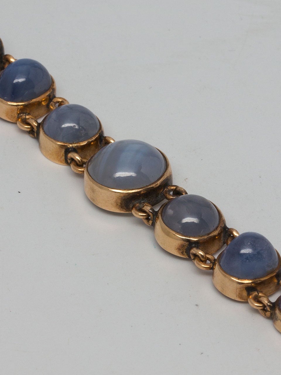 14k yellow gold with 13 bezel set natural blue star sapphires graduating in size from 11 x 11mm down to 8 x 8mm, separated by little jump rings. Very pleasing colors range from light blue to lavender. Very easy to wear & comfortable!  7