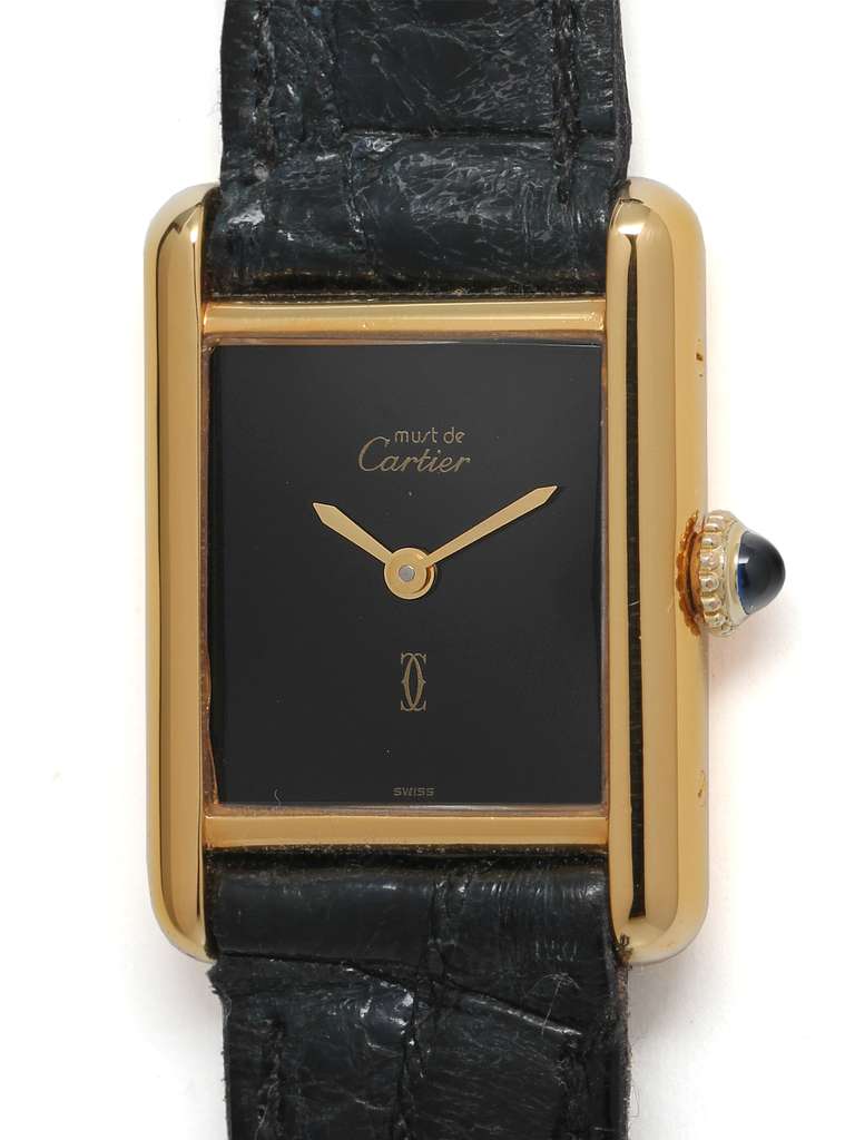 Cartier Lady's vermeil Tank Louis Must de Cartier wristwatch, circa 1990s. Vermeil, 20 microns gold over silver, case secured with screws. Classic black dial signed Must de Cartier with gilt hands and cabochon sapphire crown. 17-jewel manual-wind