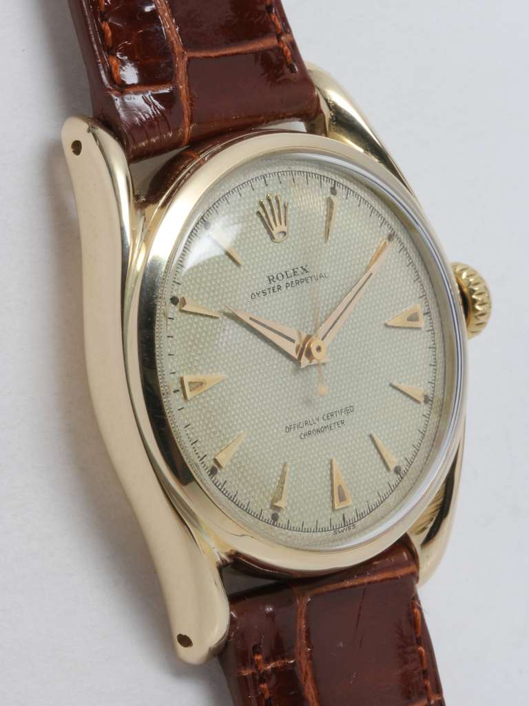Rolex 14k yellow gold Oyster Perpetual Bombe wristwatch, Ref. 6090, circa 1950s, with beautiful original silvered waffle dial with gold triangular indexes and dauphine hands. Self-winding calibre 645 movement with sweep seconds. Super Oyster crown,